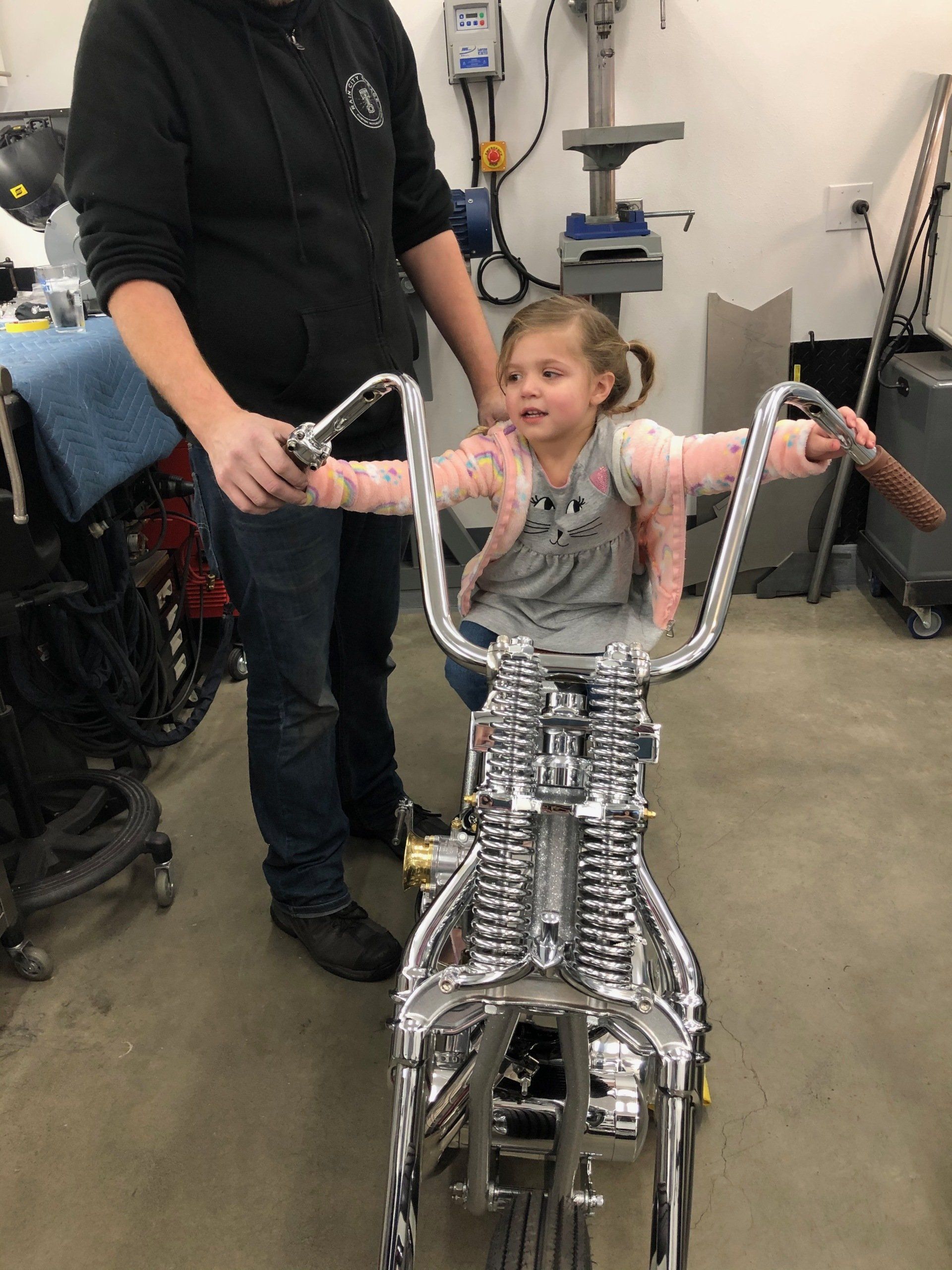 Child using a silver walker with adult assistance in a workshop setting