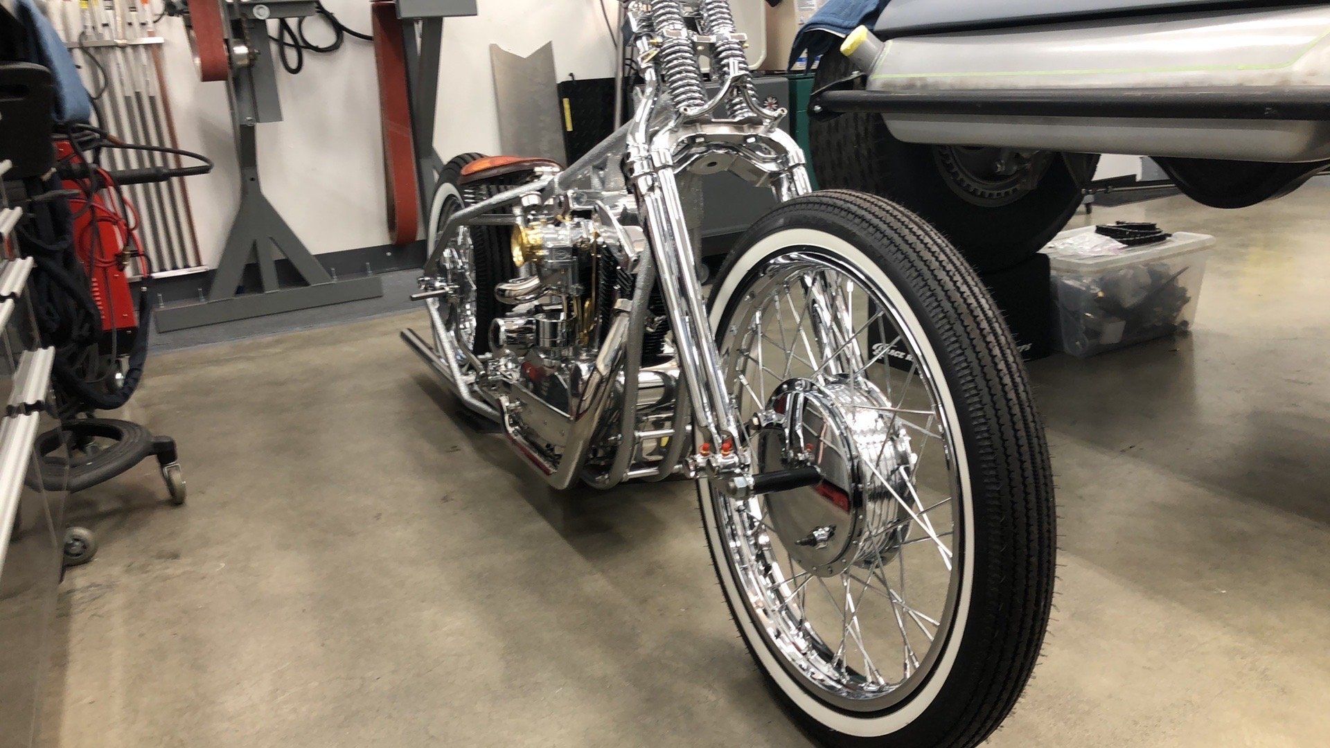 Custom chrome motorcycle in a garage, angled view from the front wheel.