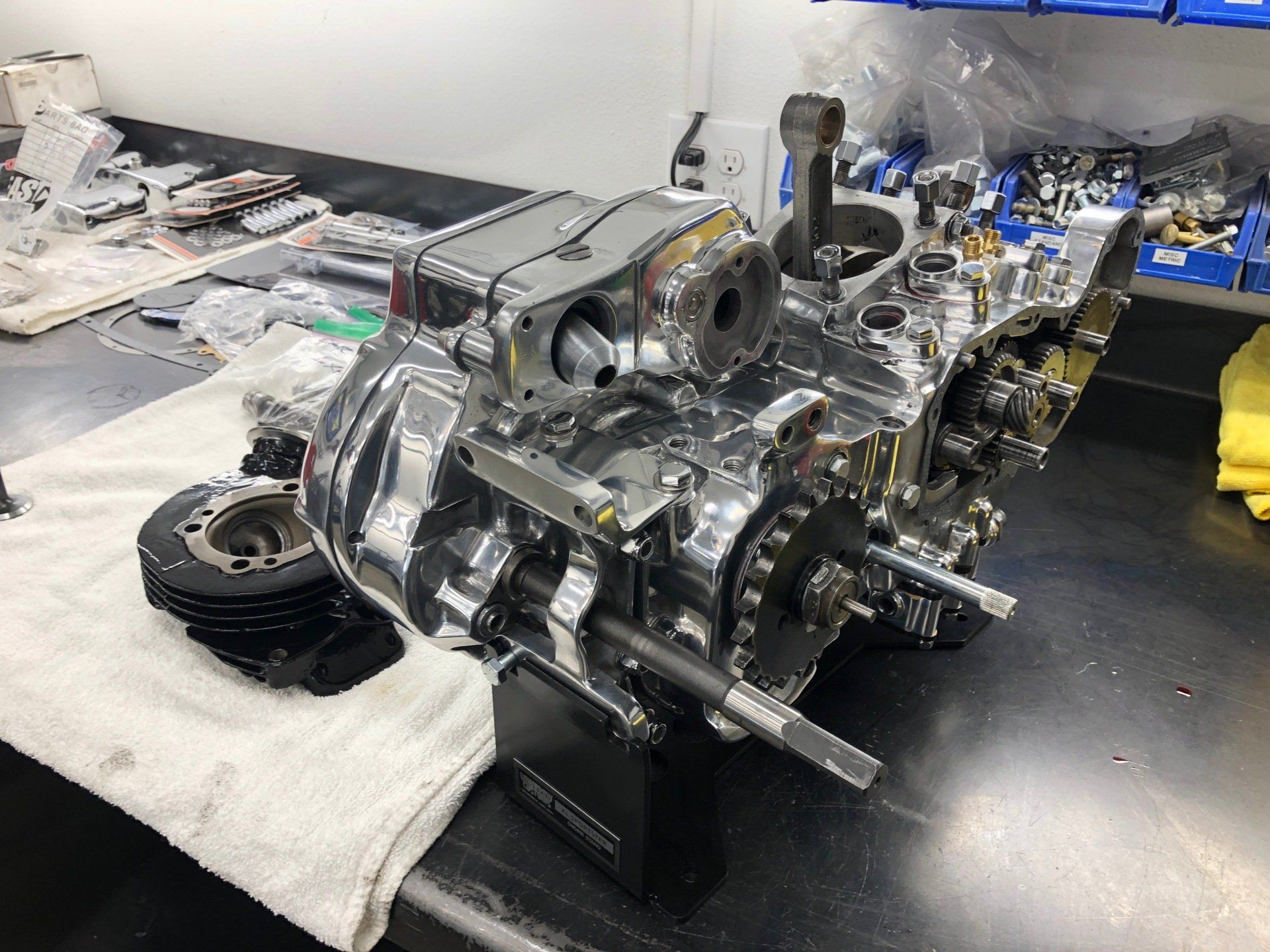 Shiny car engine on a workbench in a garage, with scattered tools and parts nearby