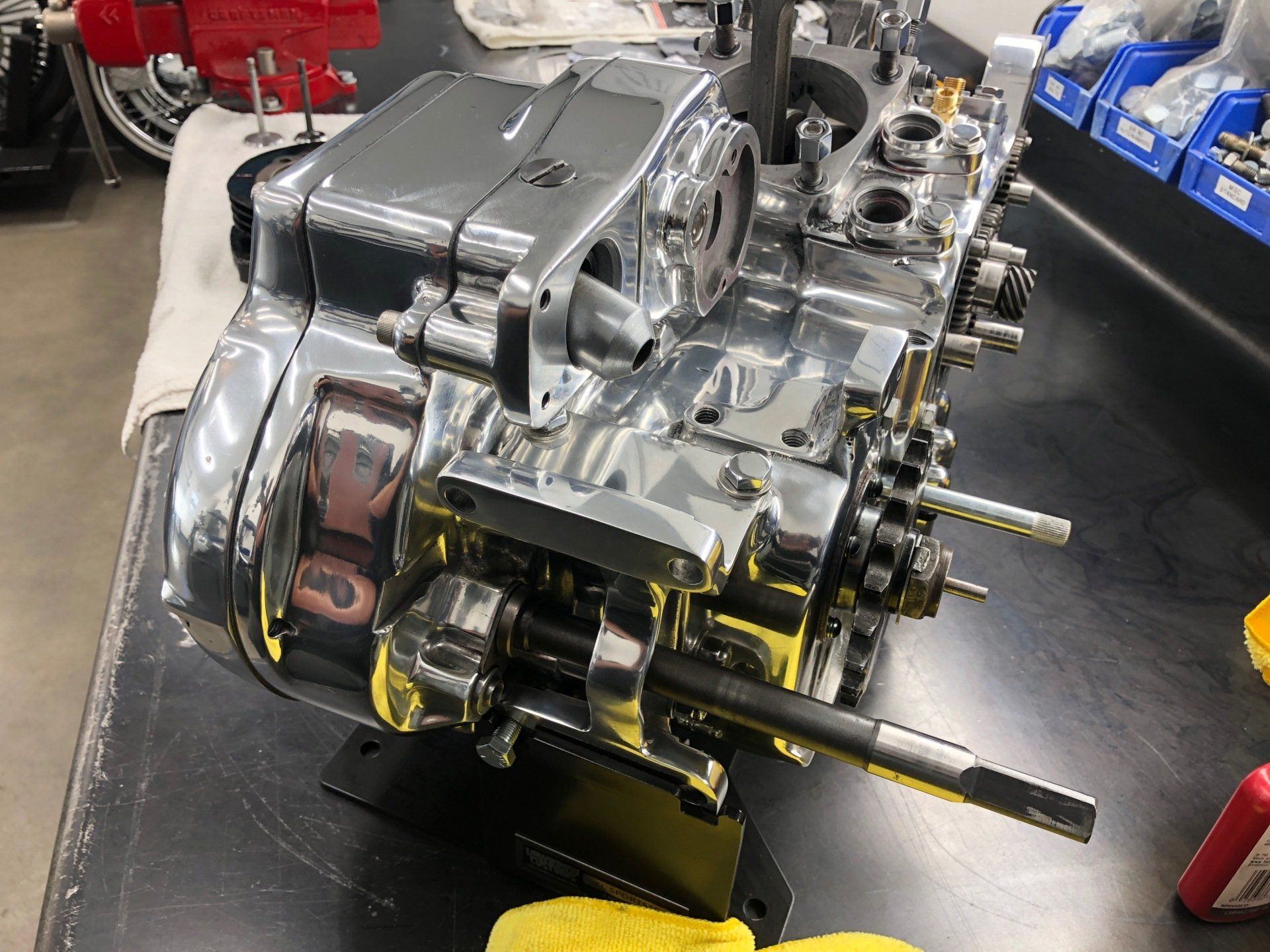 Chrome racing engine on a workshop floor, with exposed mechanical parts and blue components nearby