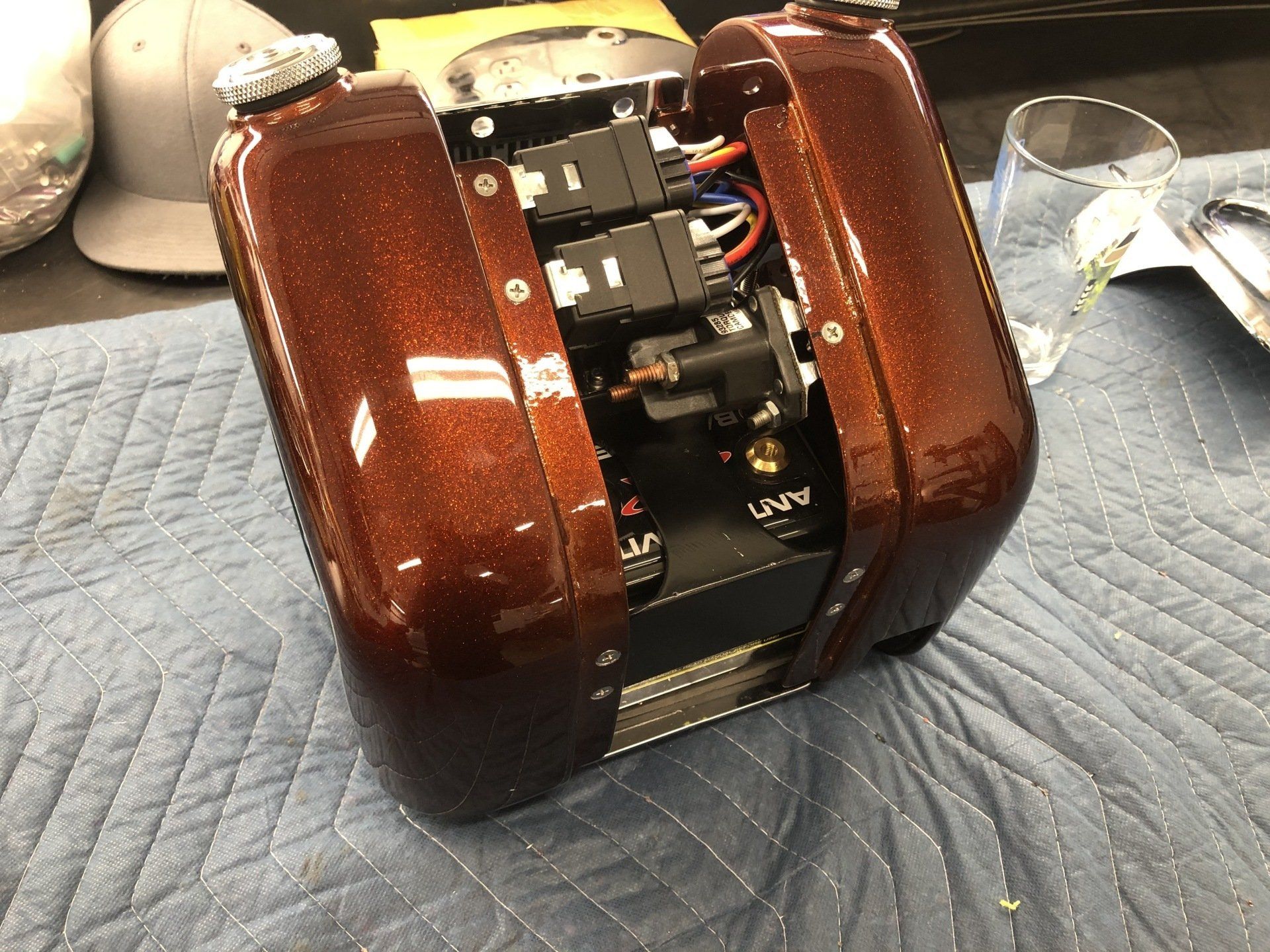 Brown electric motor or device on a quilted surface, with exposed internal components and wiring.