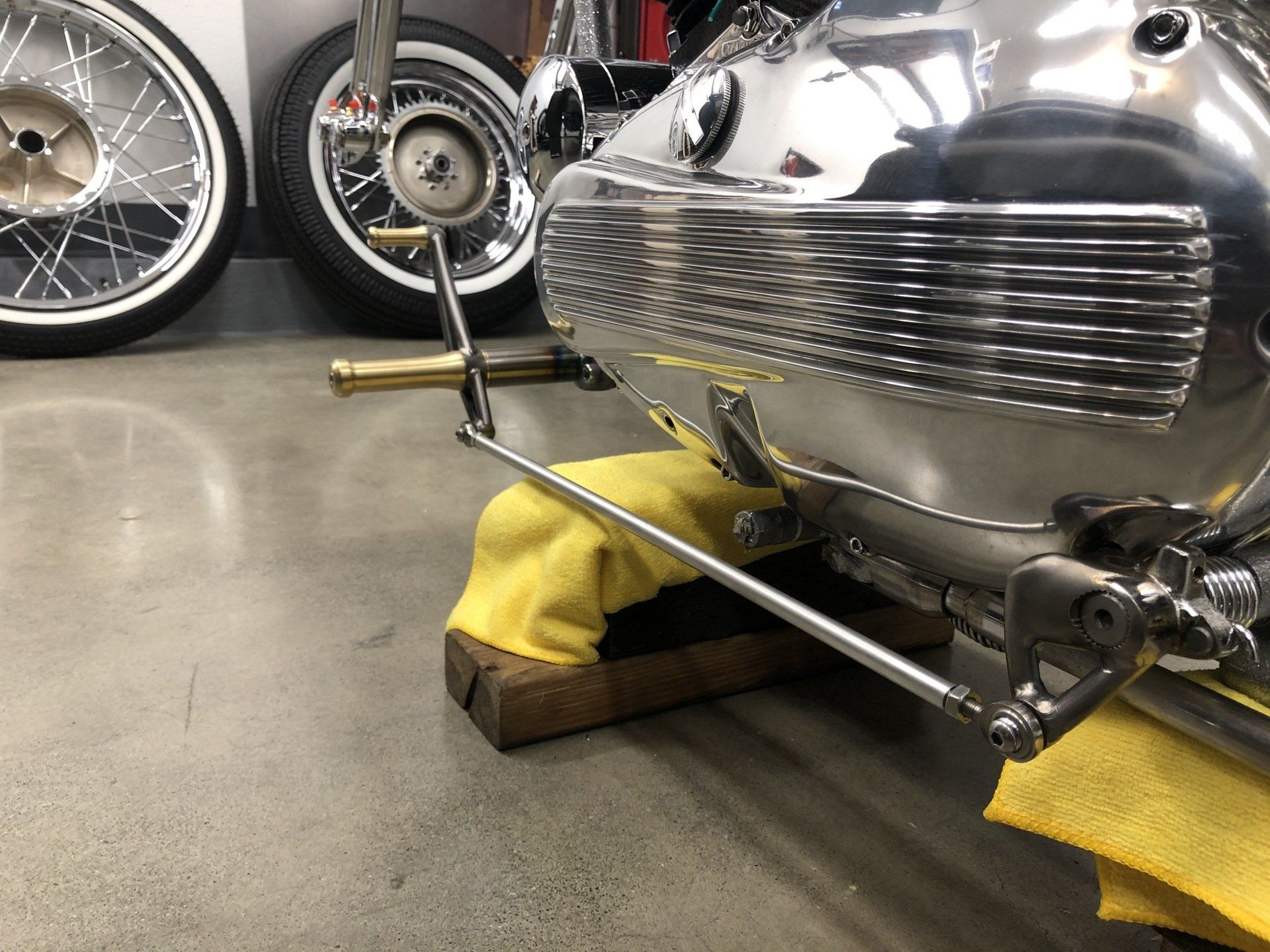 Polished silver vintage car body on yellow cloth, with wheels and tools in a workshop garage.