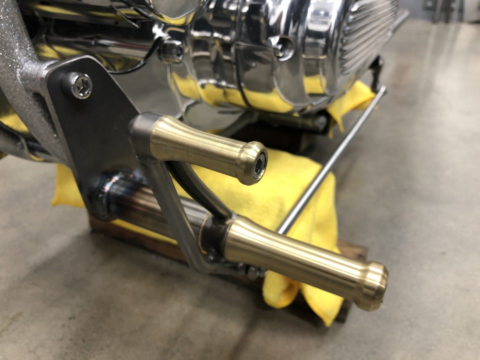 Chrome motorcycle foot pegs on a stand in a workshop
