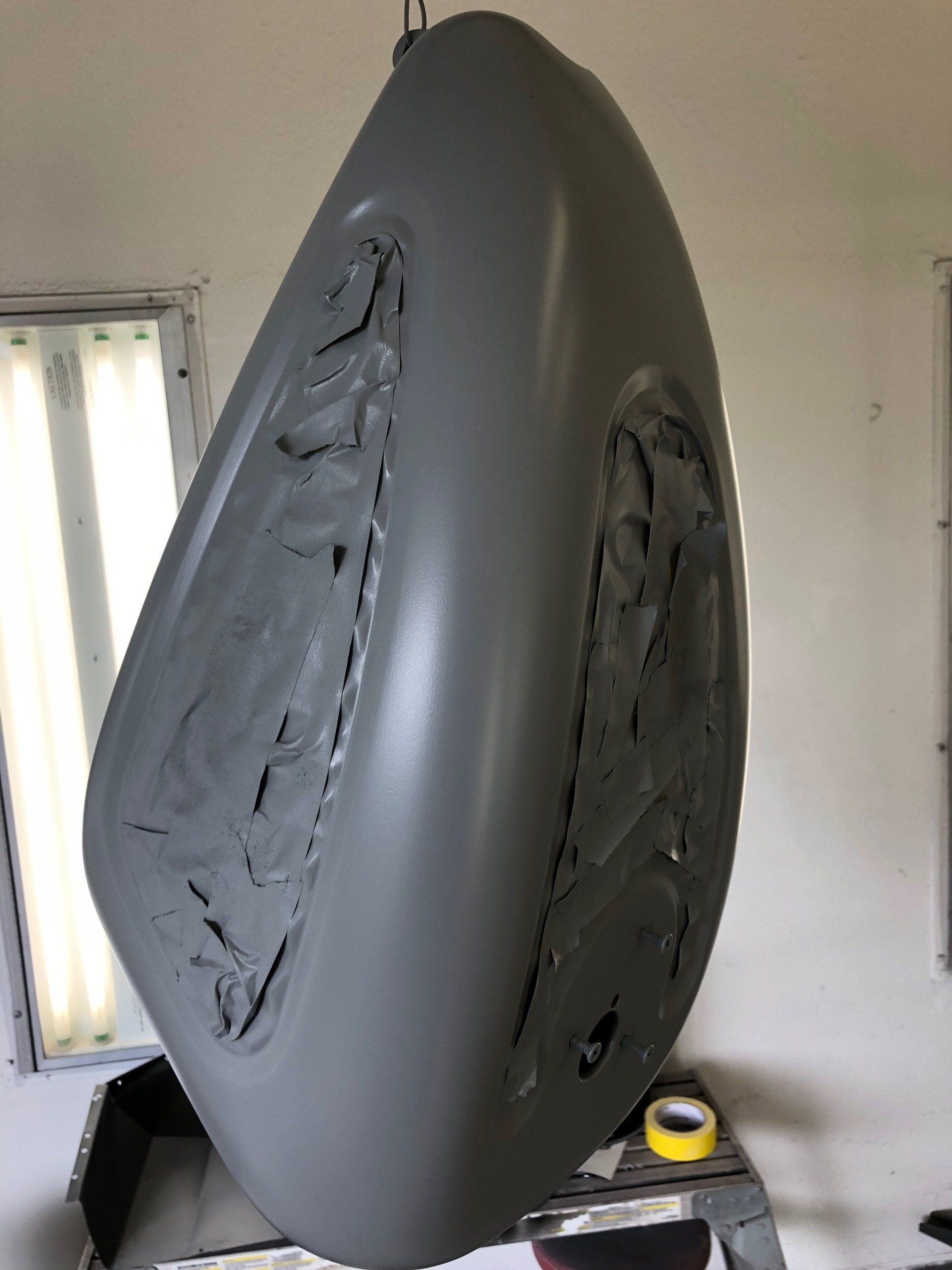 Gray abstract sculpture with two dark textured cutouts on a stand in a room