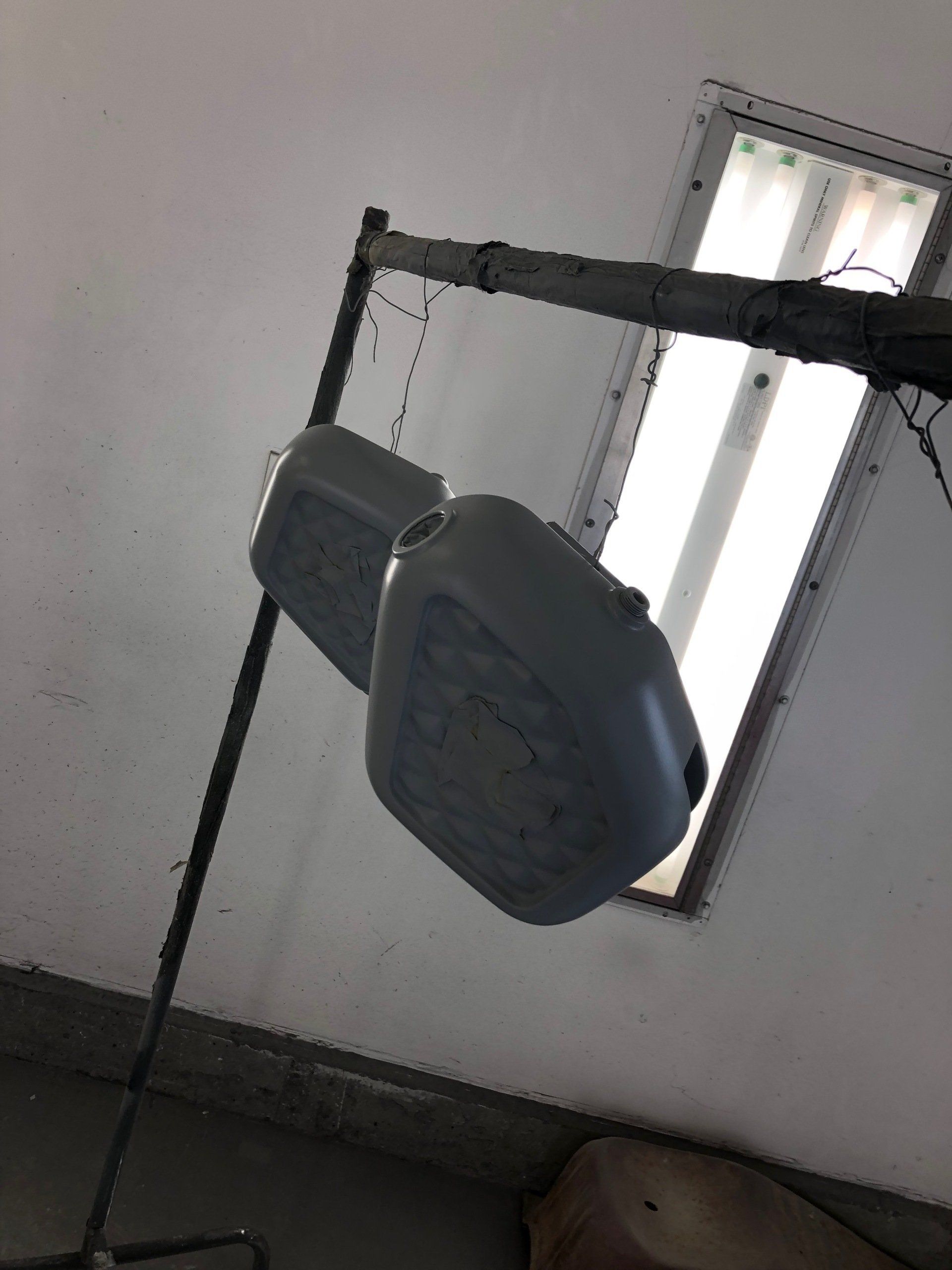 Two hanging gray exercise pads near a window in a dim room