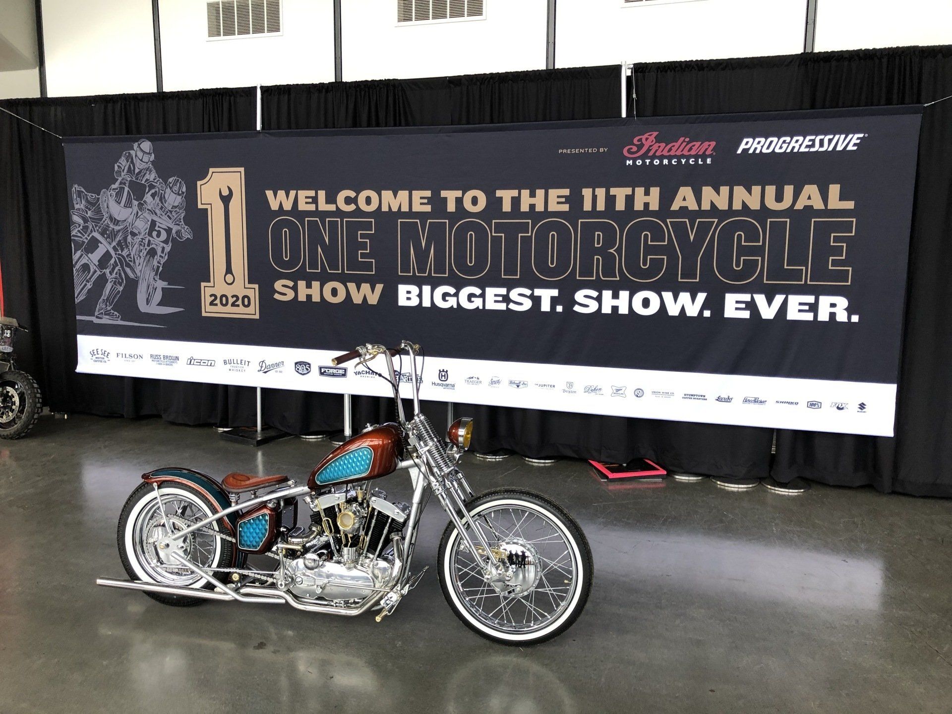 Custom motorcycle at the 11th Annual One Motorcycle Show banner indoors