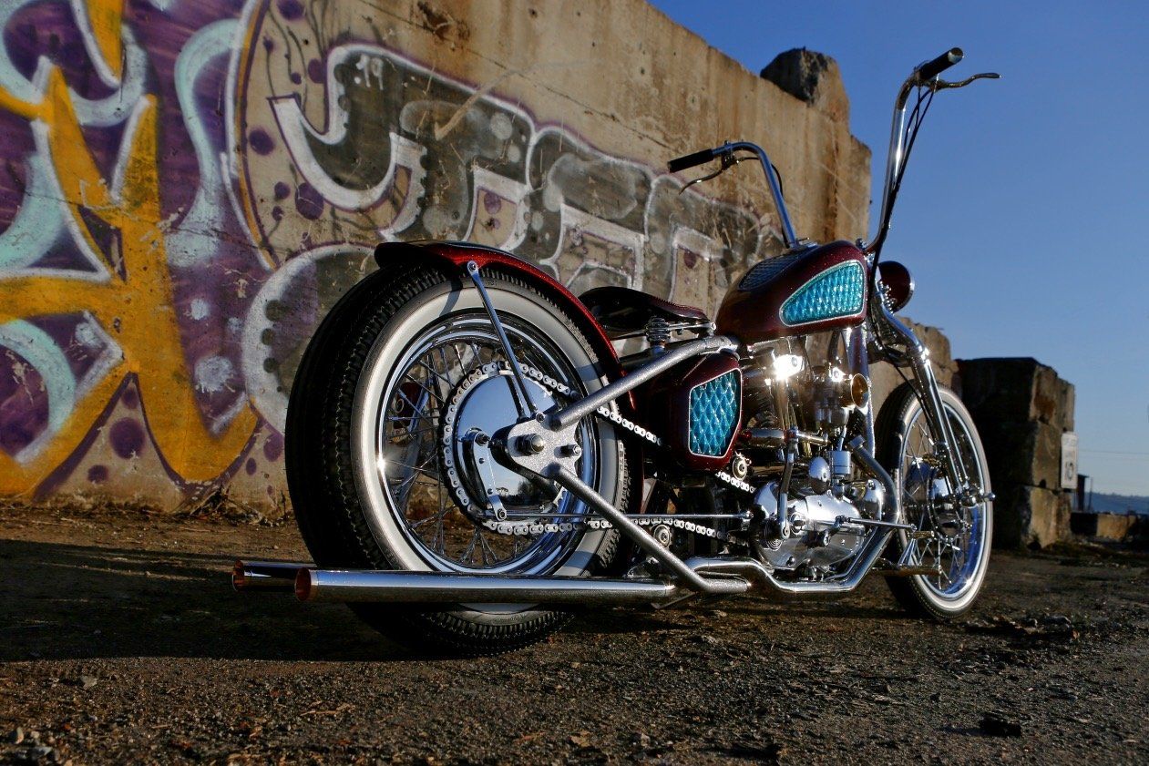 Chrome motorcycle parked by a graffiti-covered wall at dusk