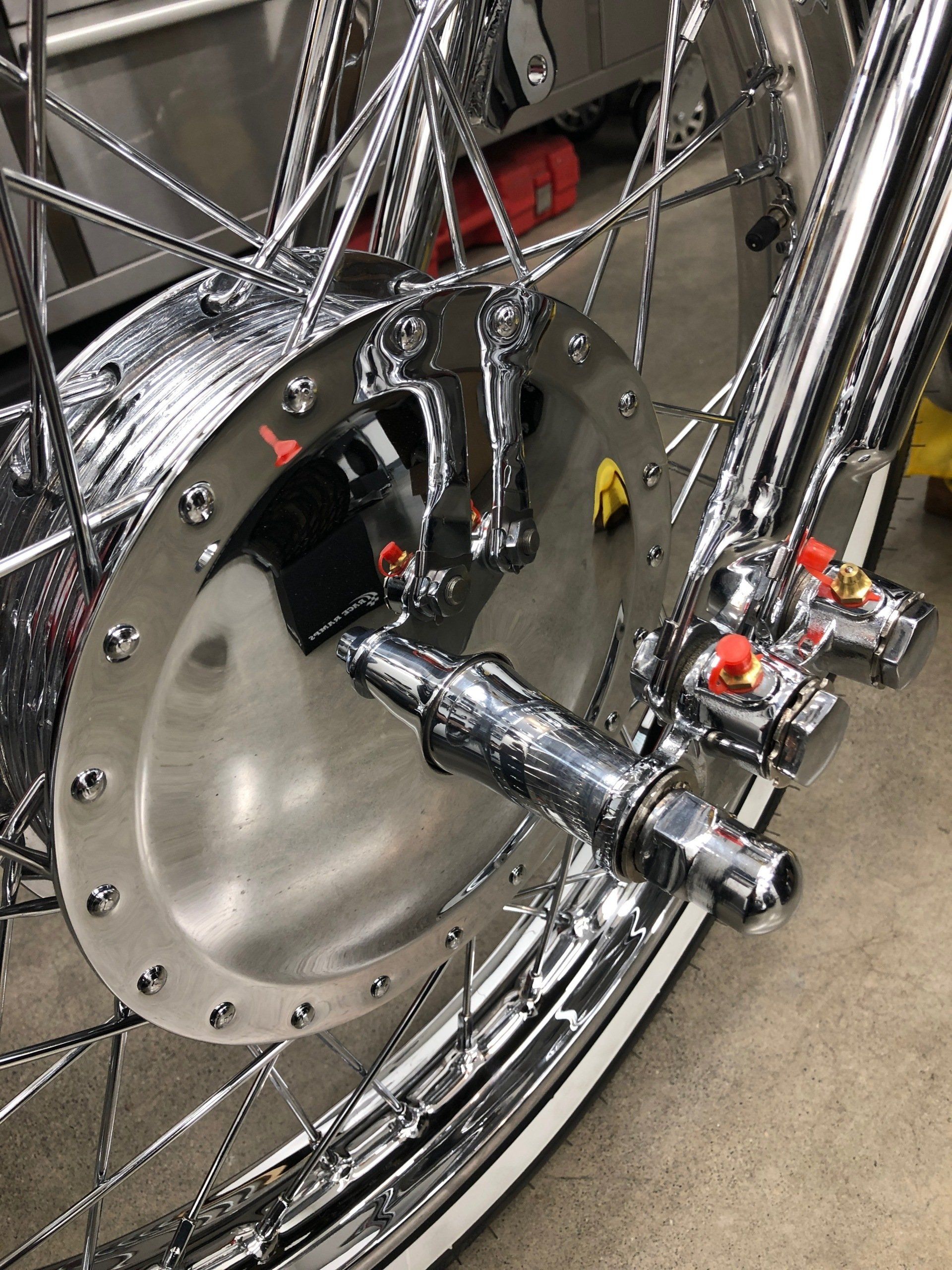 Chrome-plated bicycle wheel and rear drivetrain close-up on a concrete floor