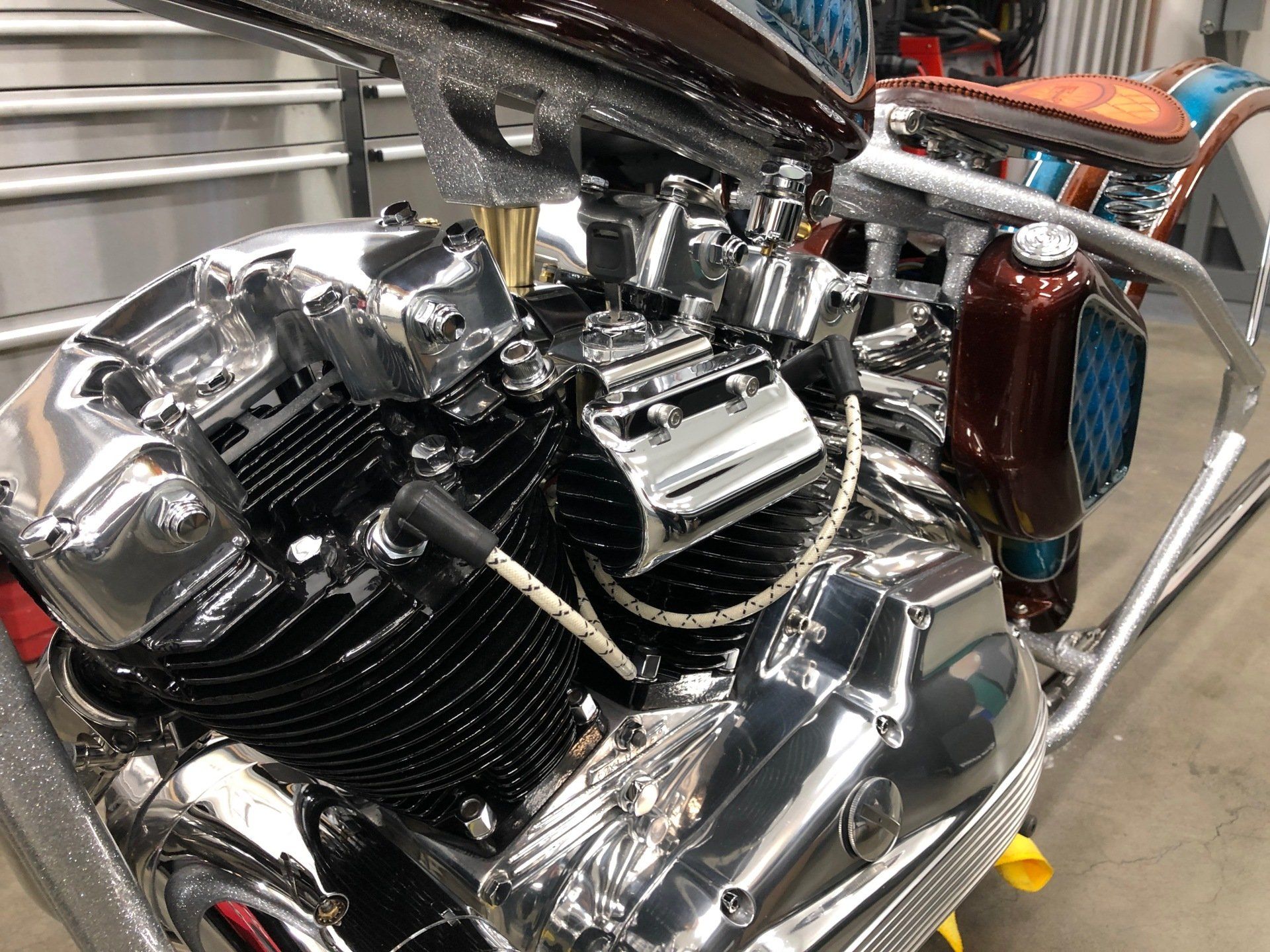 Chrome motorcycle engine close-up with black fins and polished metal parts, mounted in a garage or workshop