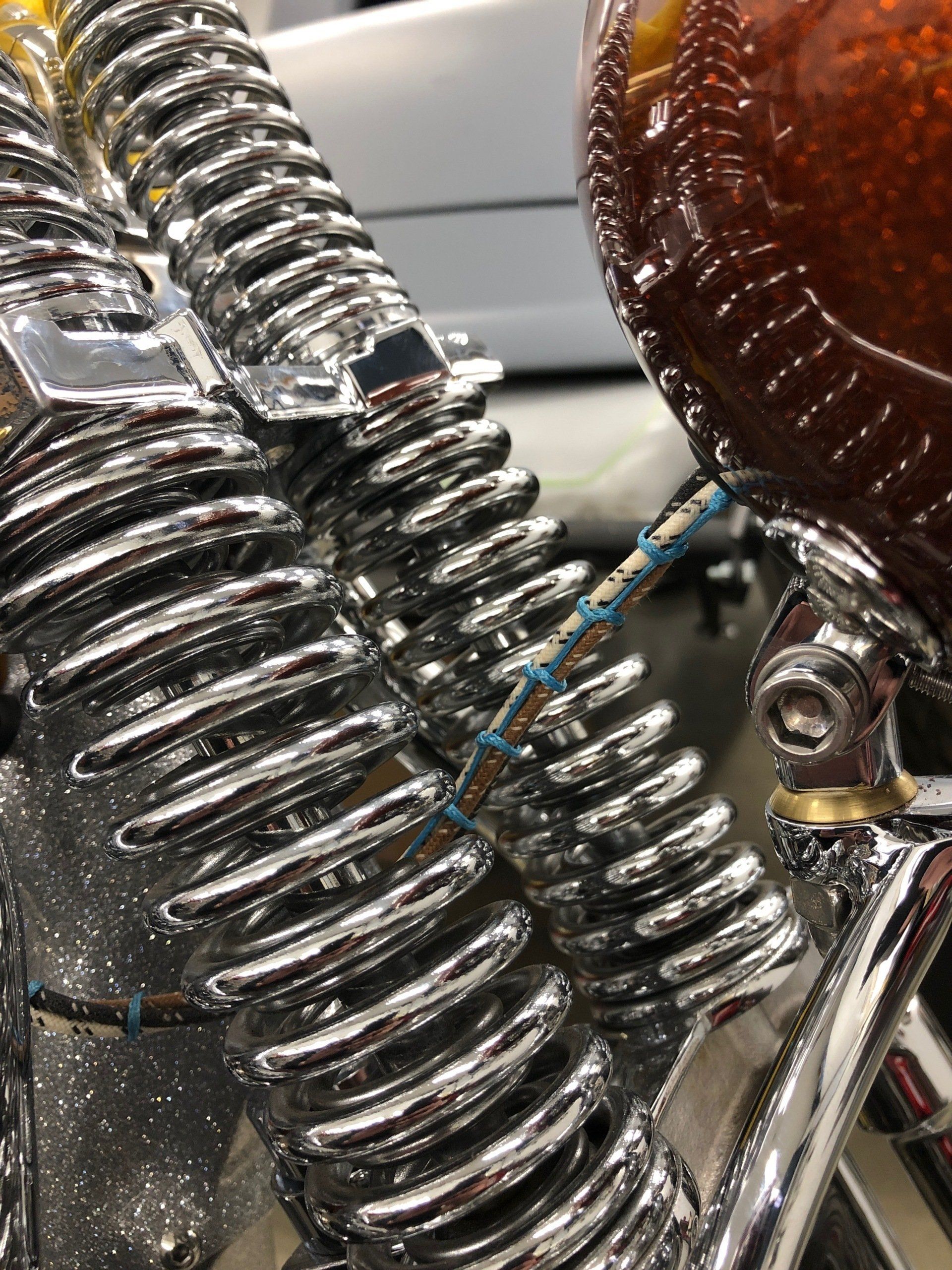 Close-up of shiny chrome motorcycle springs and a brown leather seat