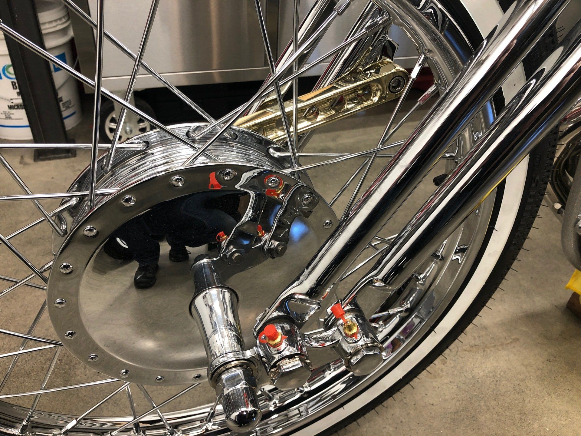 Chrome bicycle wheel with intricate spokes and black frame detail in a workshop setting