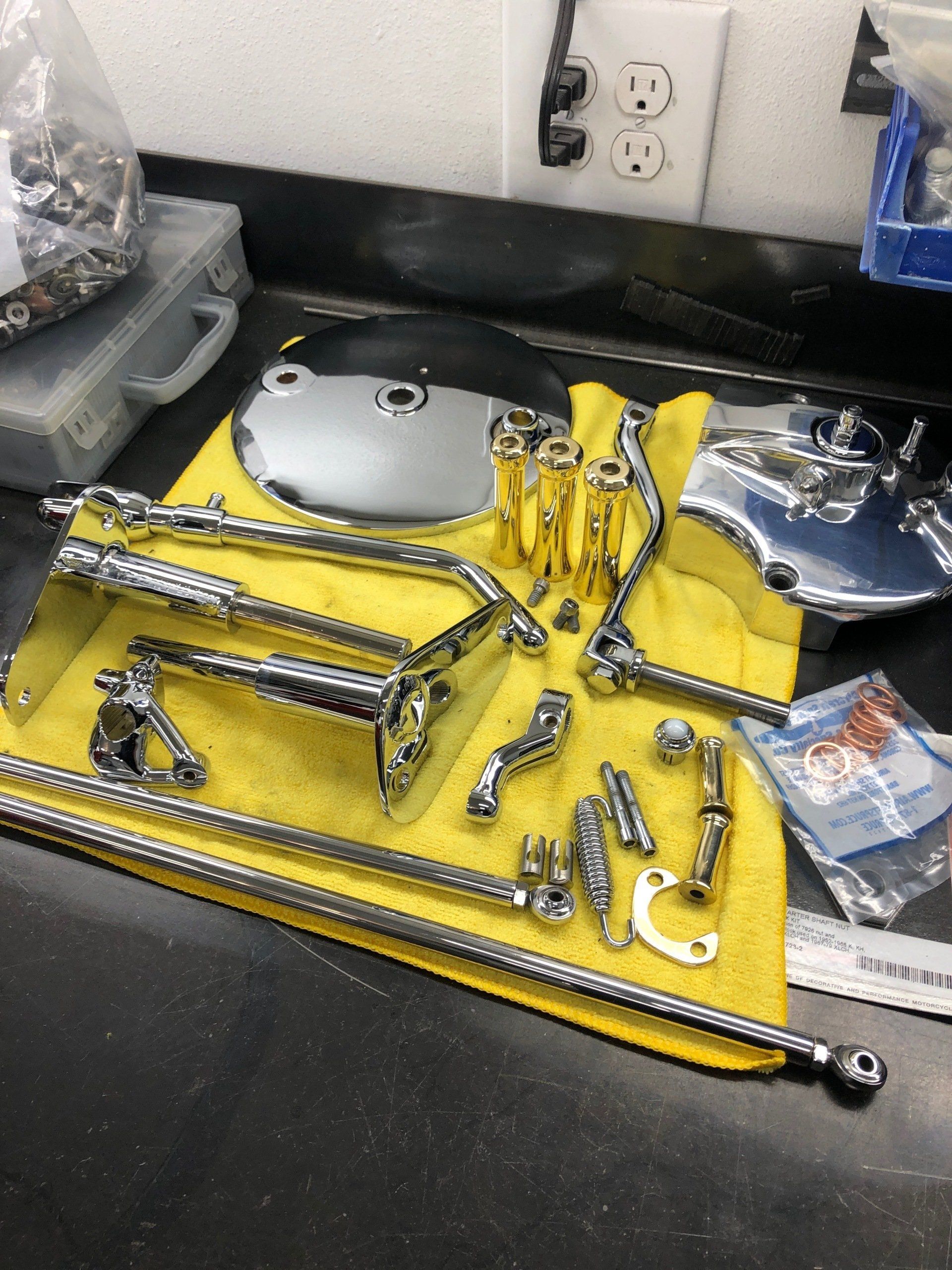 Surgical instruments laid out on a yellow sterile drape on a black countertop by a wall outlet.