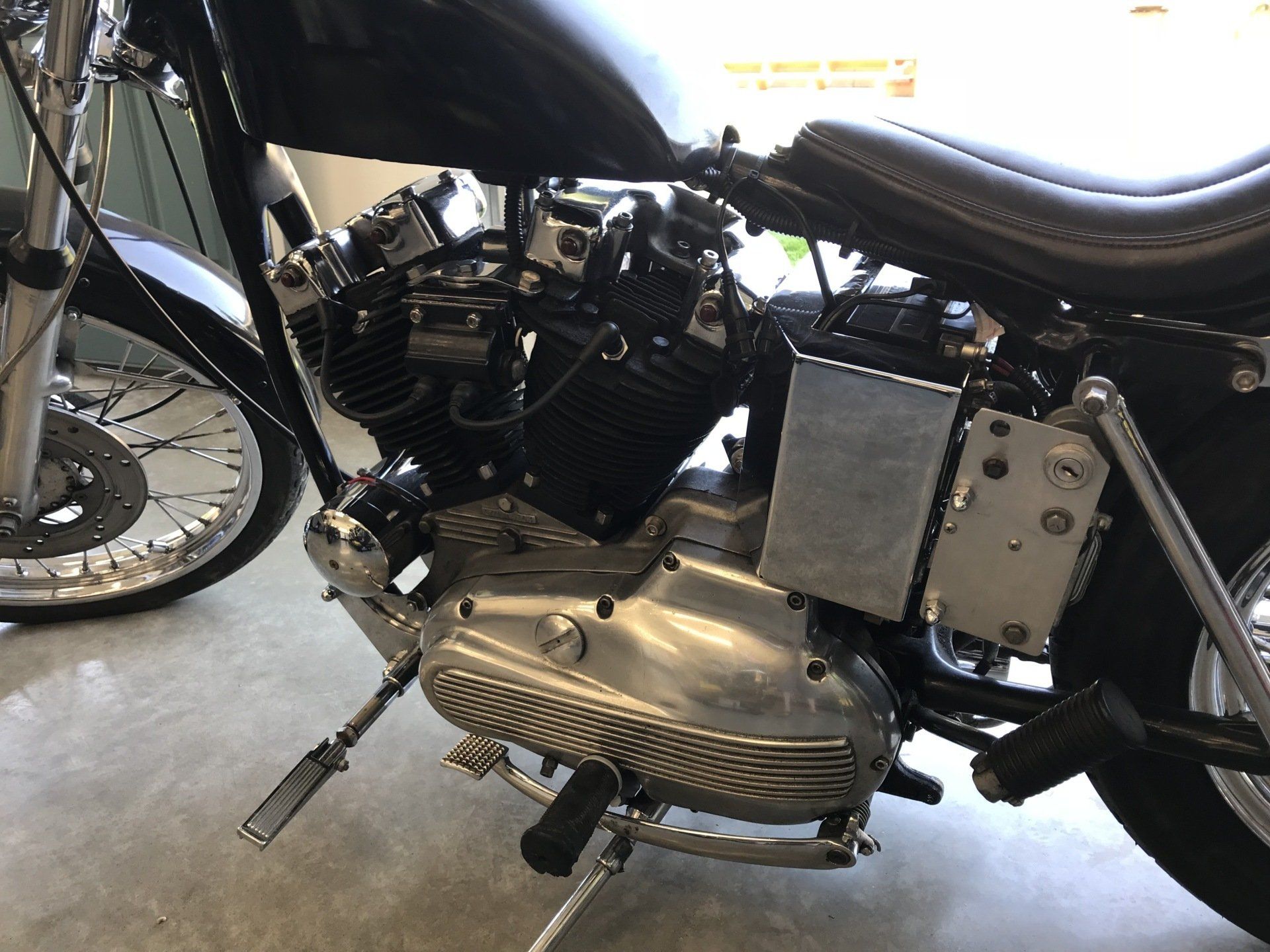 Close-up of a motorcycle engine and chrome exhaust in a garage.