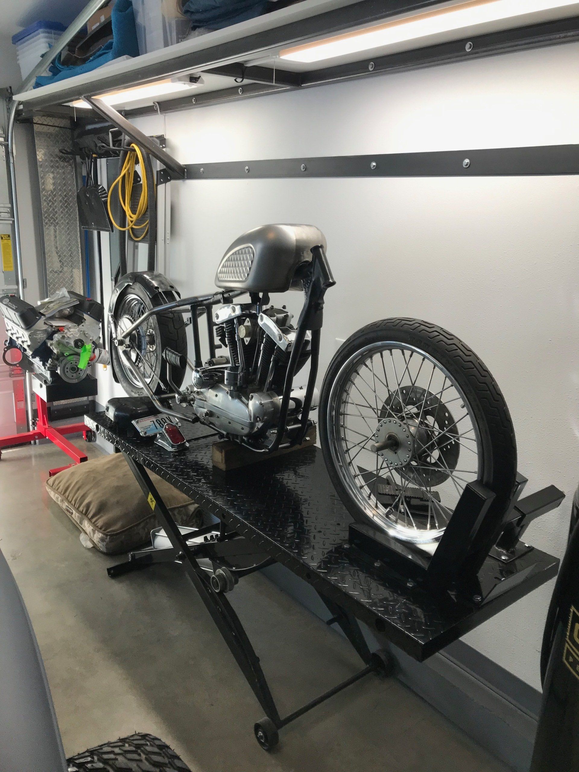 Motorcycle on a lift in a garage, with a detached rear wheel and exposed engine.