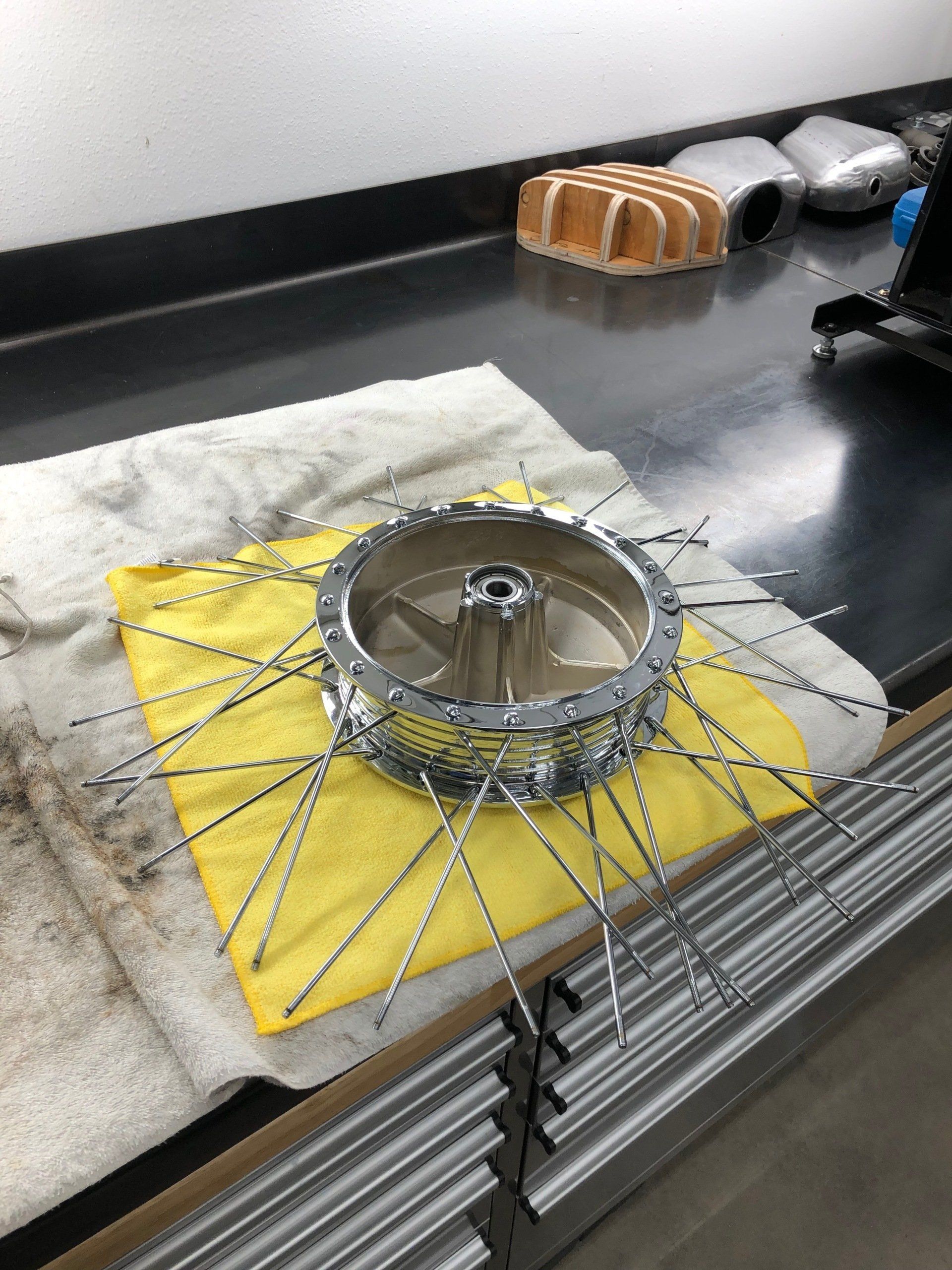 Tire chained for traction on a yellow mat in a workshop, with tools and supplies nearby.