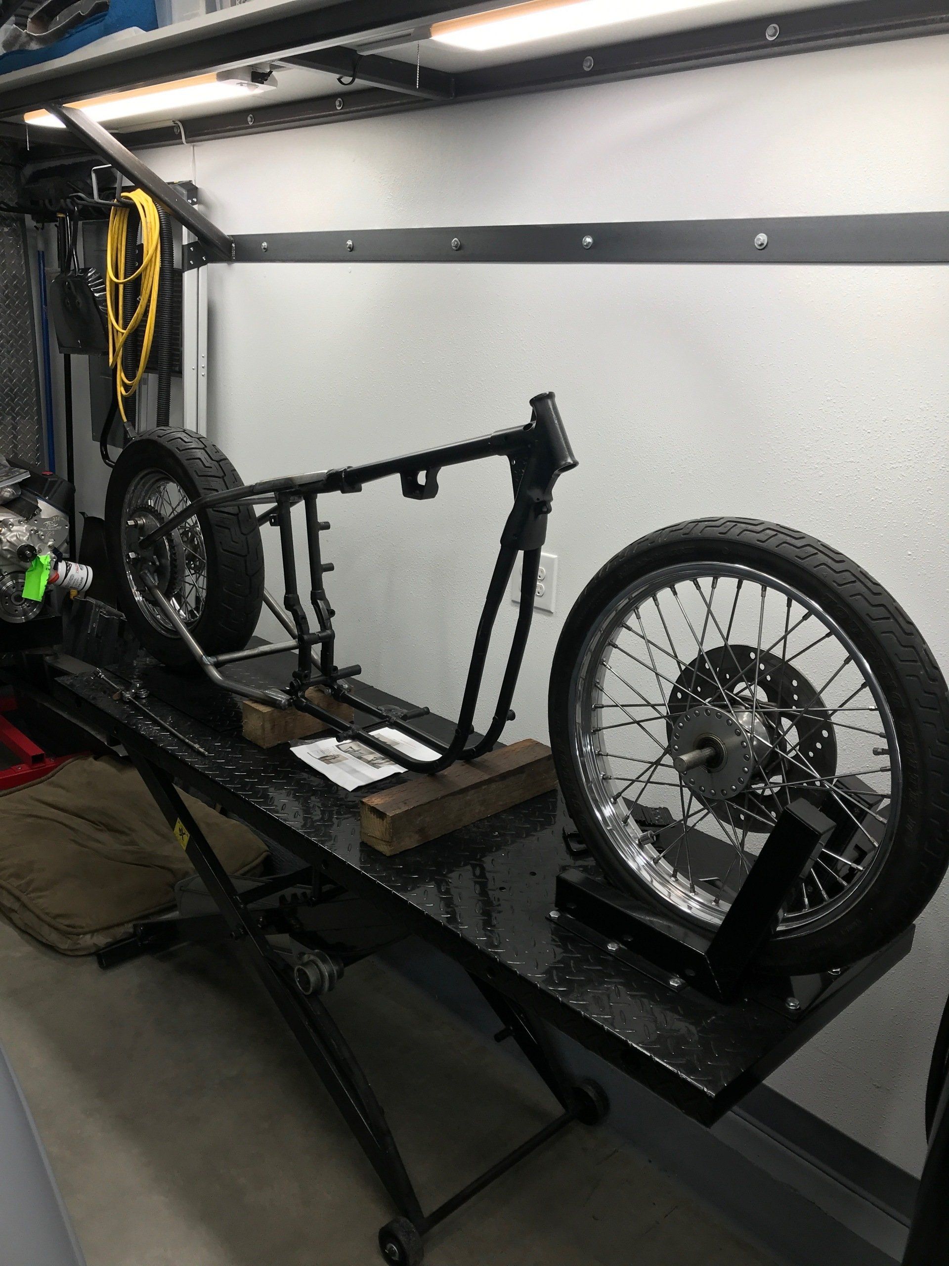 Black electric bike frame with two wheels on a work stand in a garage or workshop
