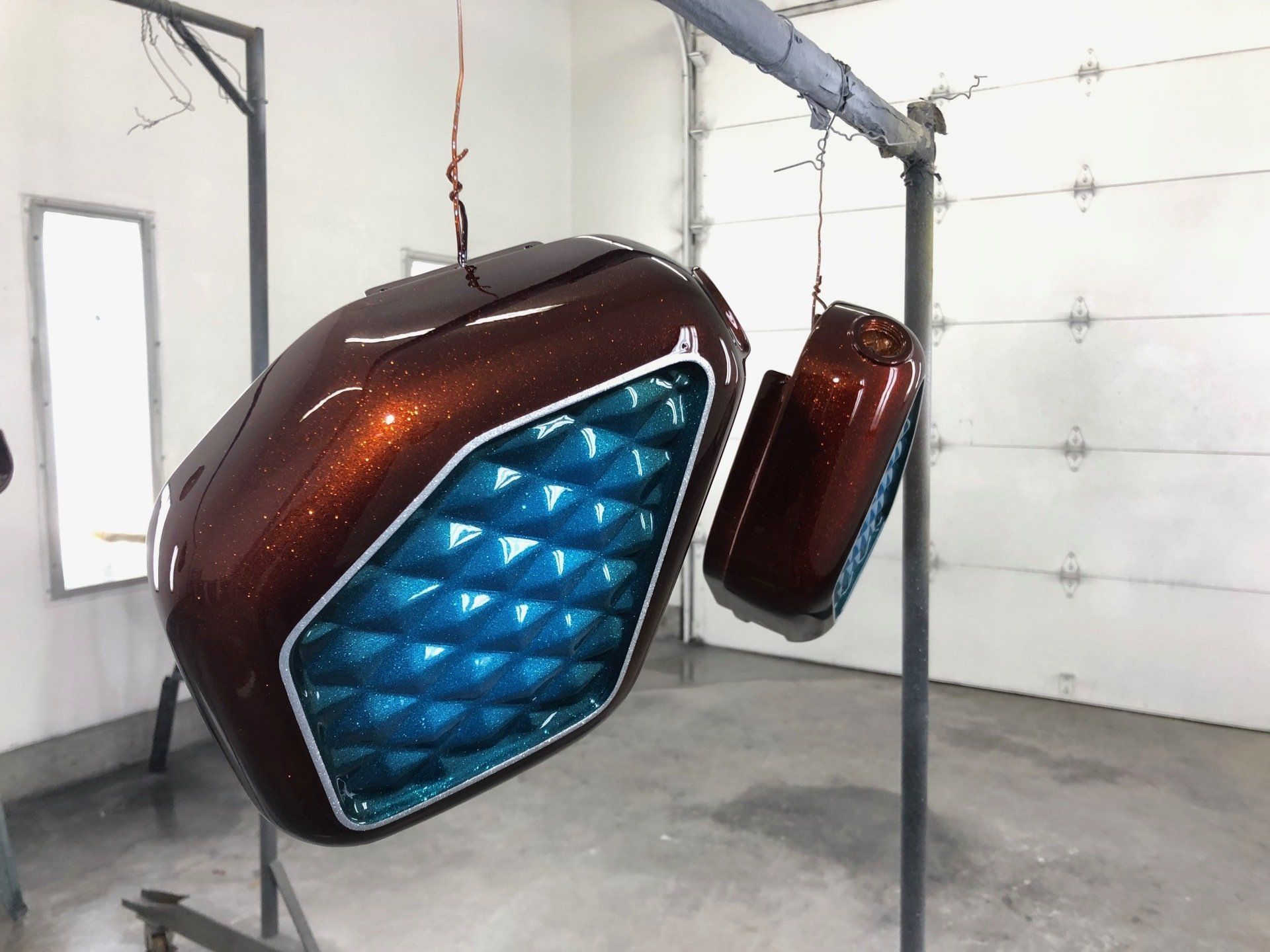 Two metallic blue-and-brown hanging pod seats in a workshop-like room