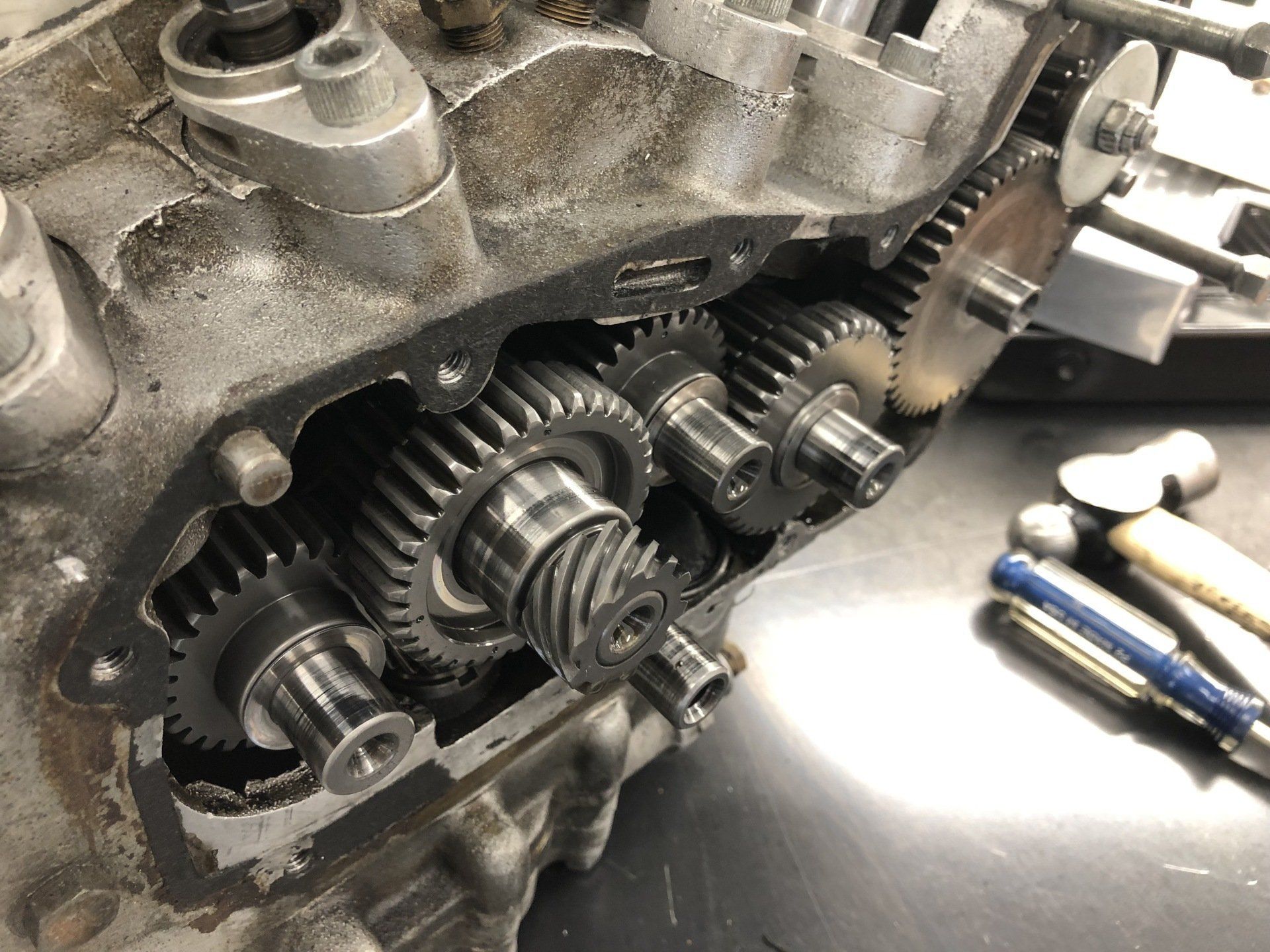 Open engine gearbox with exposed gears and shafts on a workbench, with tools nearby