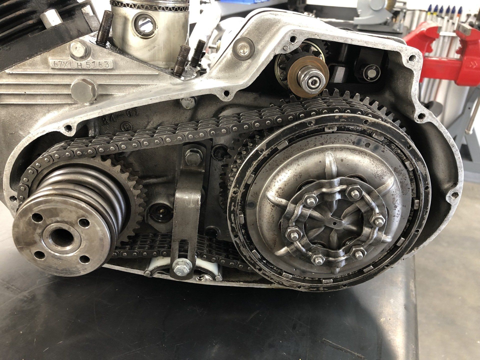 Open engine with exposed timing chain, pulleys, and metal components in a workshop