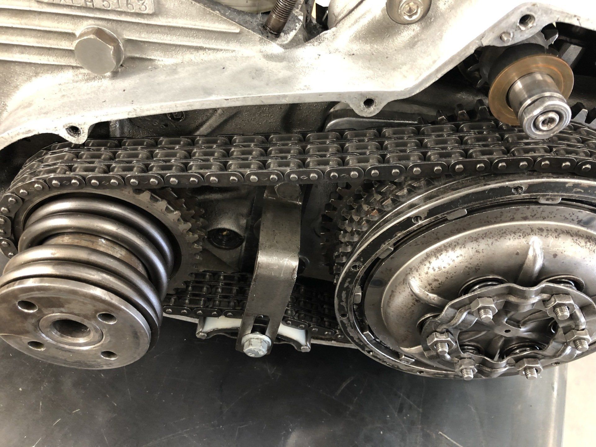 Close-up of a motorcycle engine, chain, and rear sprocket under the frame