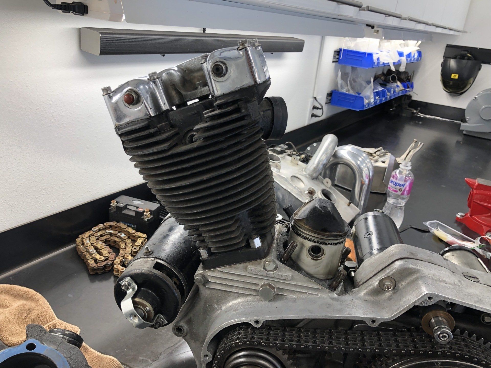 Motorcycle engine on a workbench, with chrome parts and tools in a workshop