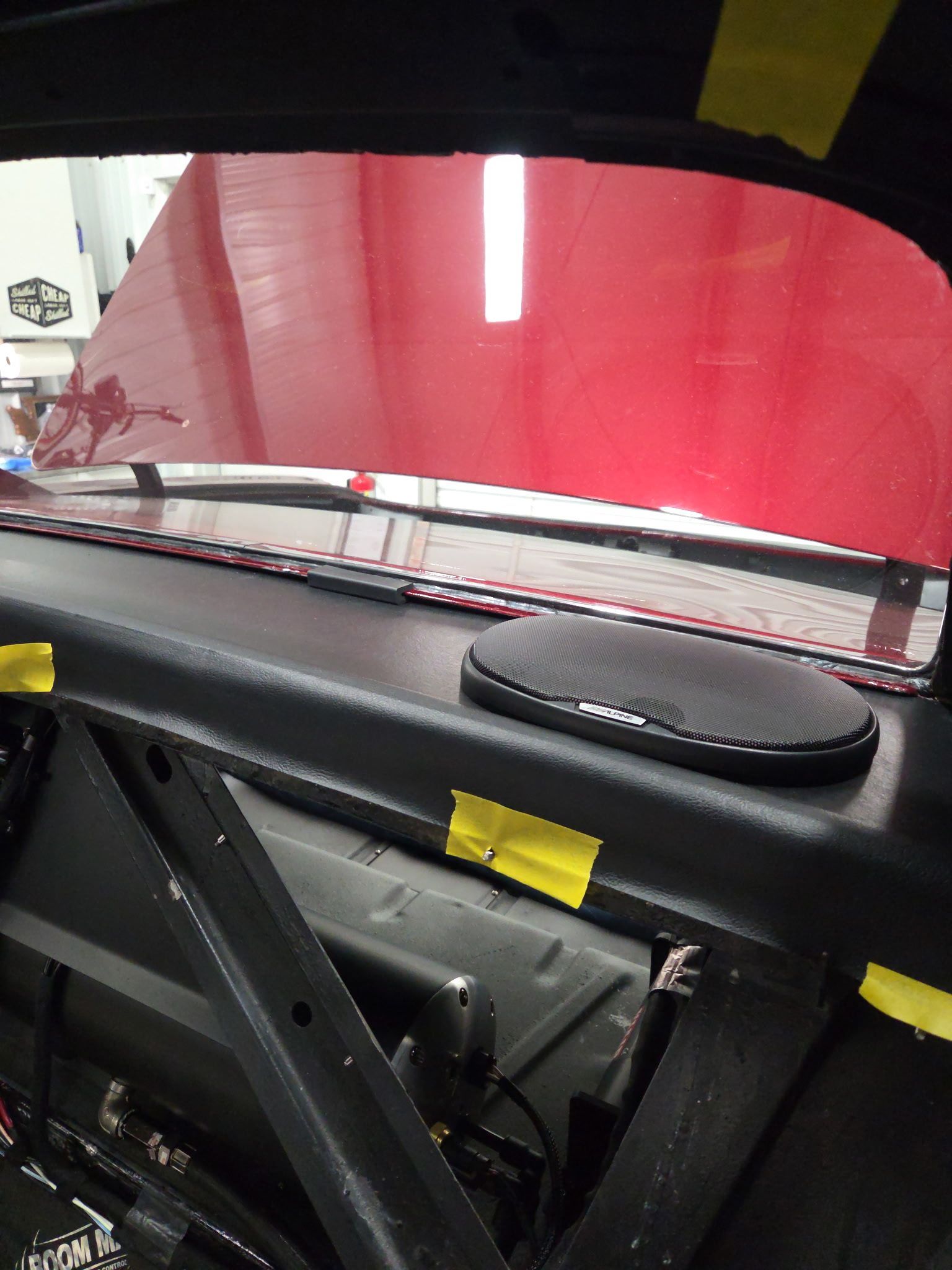 Car interior with a red windshield sunshade and a black dashboard panel with yellow tape.