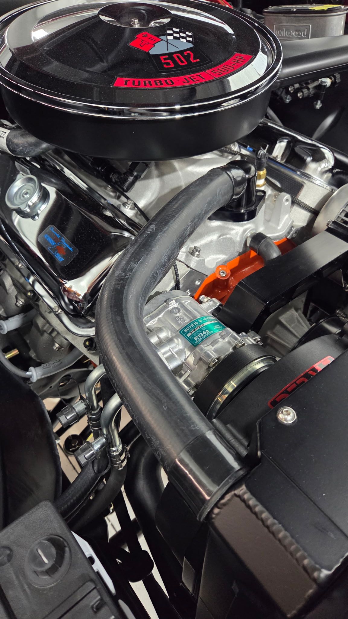Chrome car engine with black air filter housing, red accents, and visible hoses in a close-up underhood view