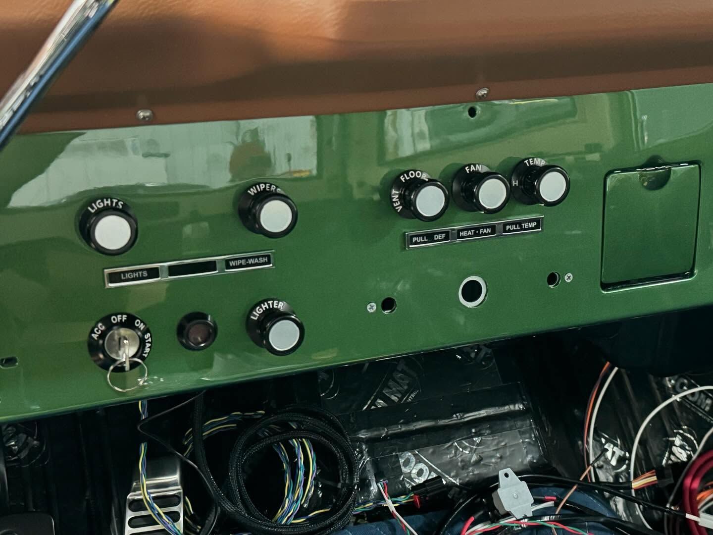 Green control panel with knobs and switches above a compartment of tangled wires