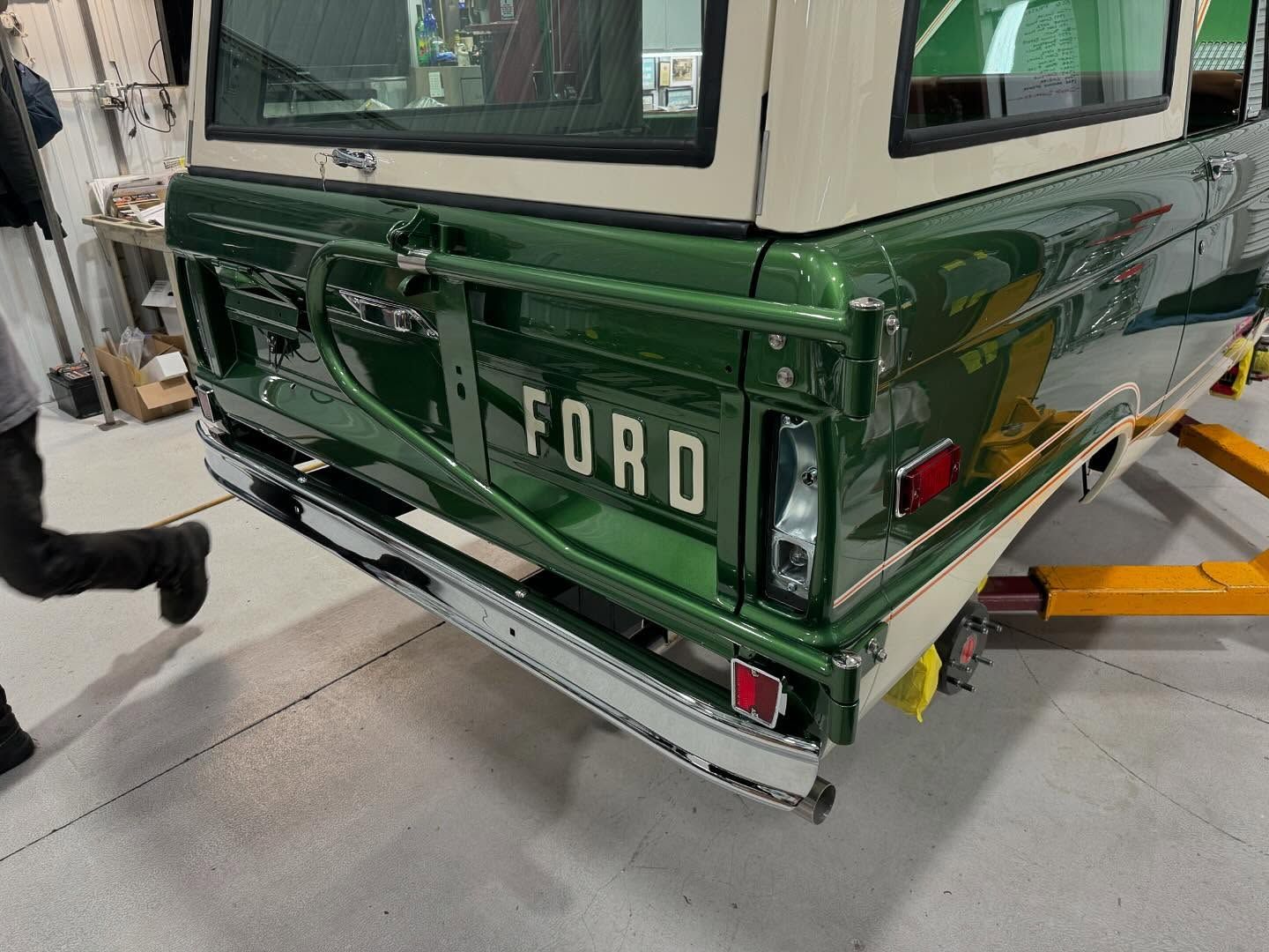 Rear of a dark green Ford SUV in a garage, showing the tailgate and chrome bumper