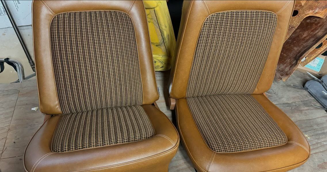 Two tan woven seat cushions side by side on brown chairs, with one cushion slightly tilted.