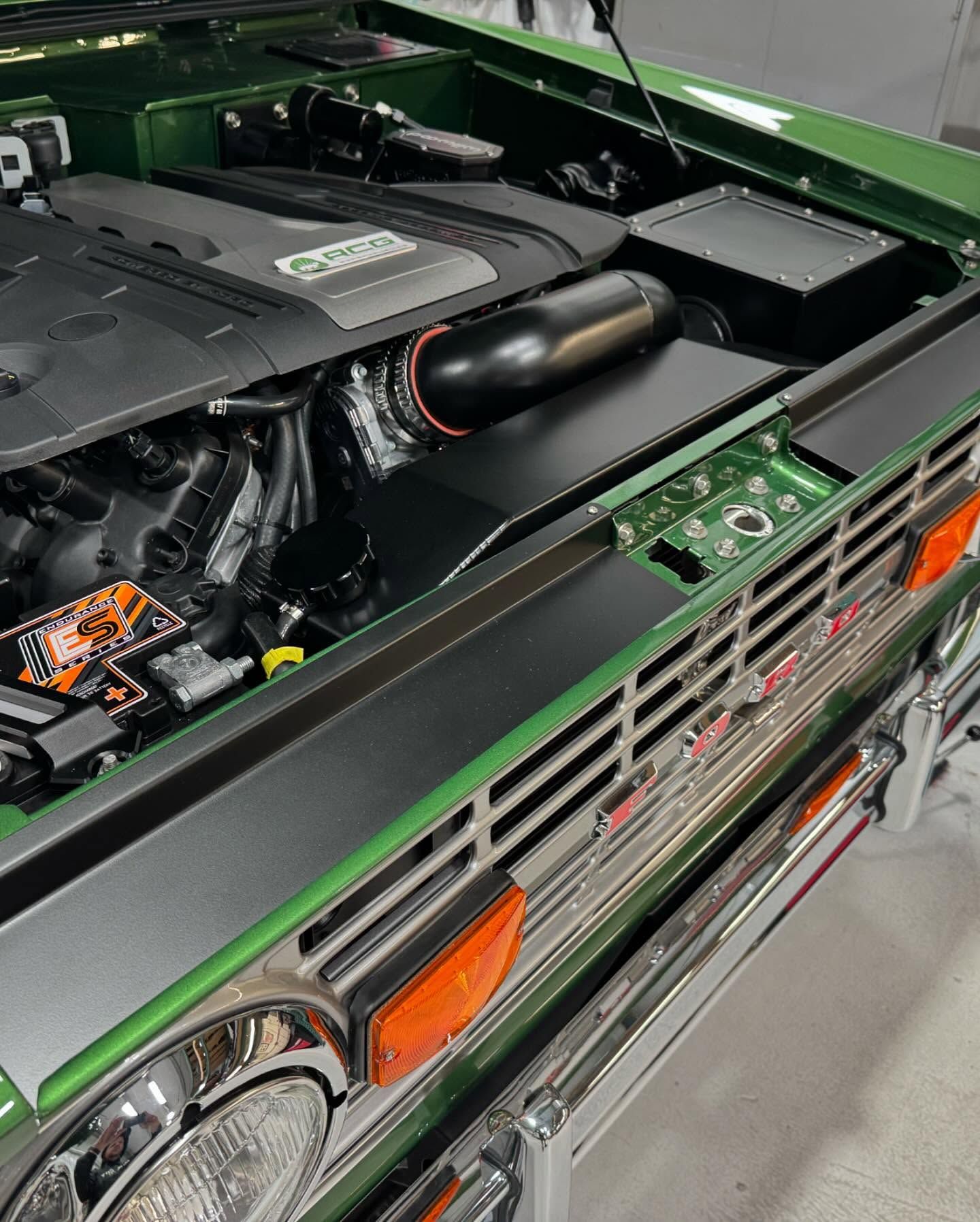 Green classic car with hood open, showing the engine compartment and front grille.