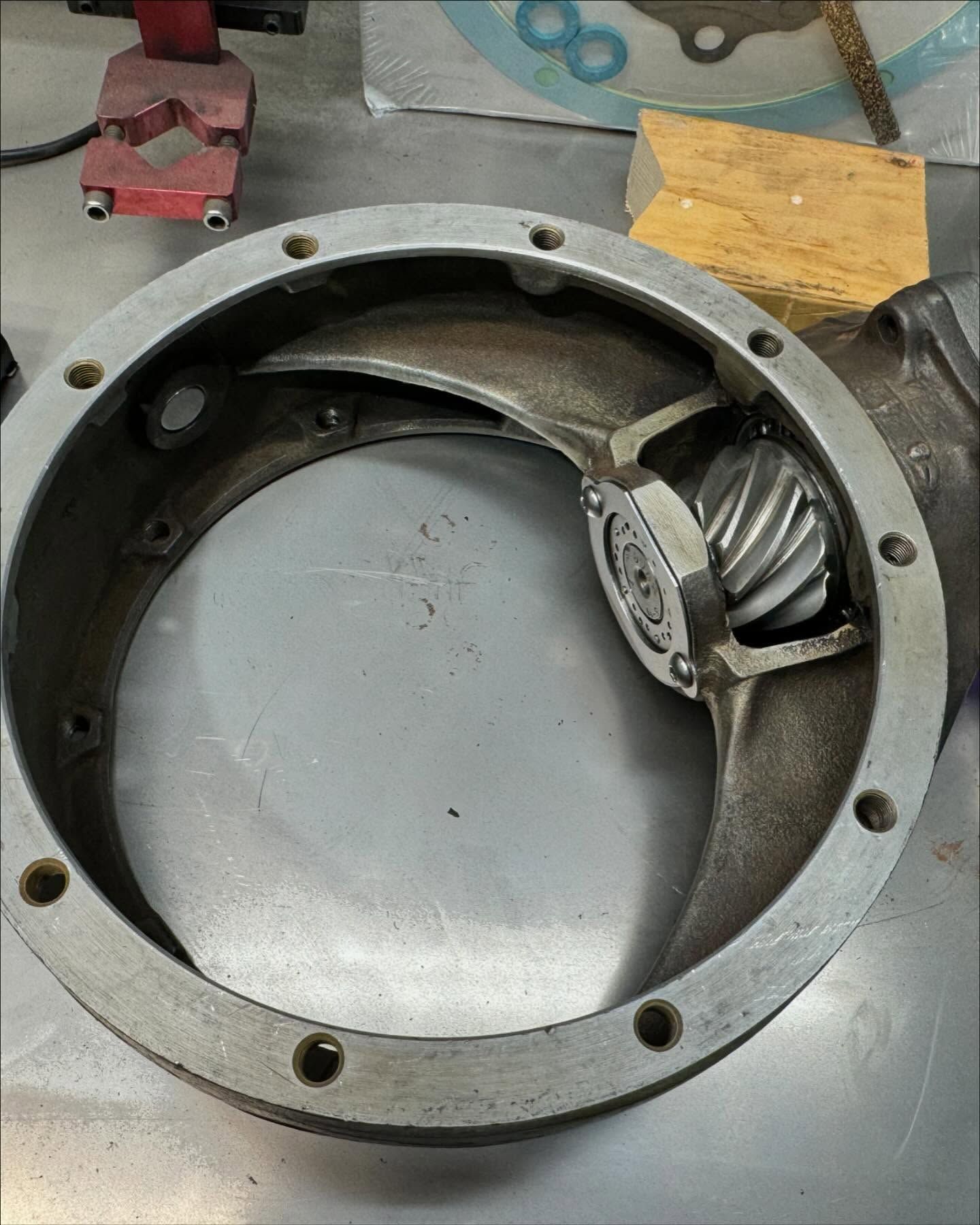 Metal bearing housing with a helical gear inside, resting on a workshop bench