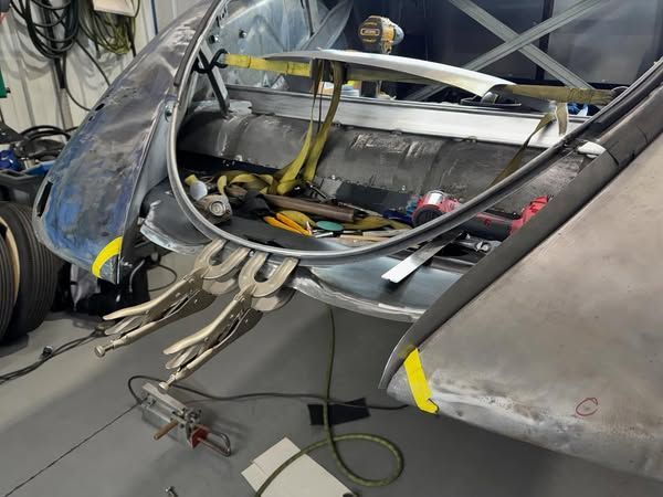 Wiring and metal frame inside a damaged gray vehicle or aircraft cockpit under repair