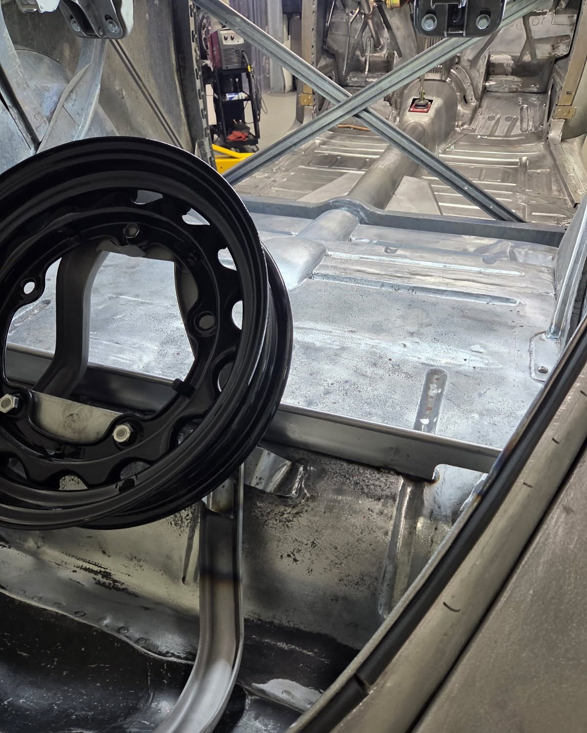 Black wheel rim resting on a metal platform inside an industrial vehicle or workshop frame.
