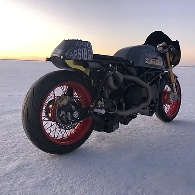 Custom black motorcycle with red wheels on a snowy landscape at sunset