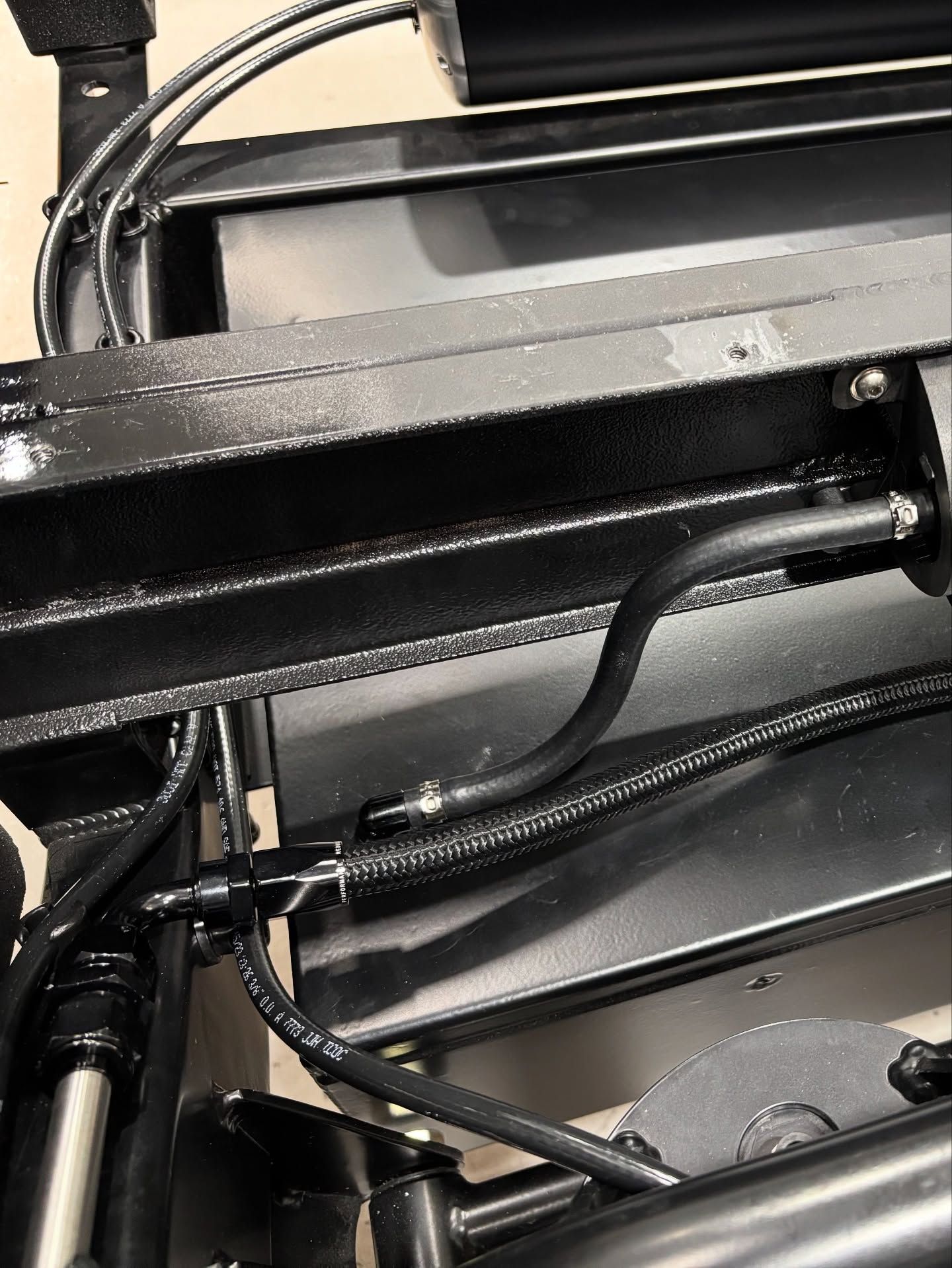 Close-up of black metal tubing and cables inside a machine or vehicle compartment