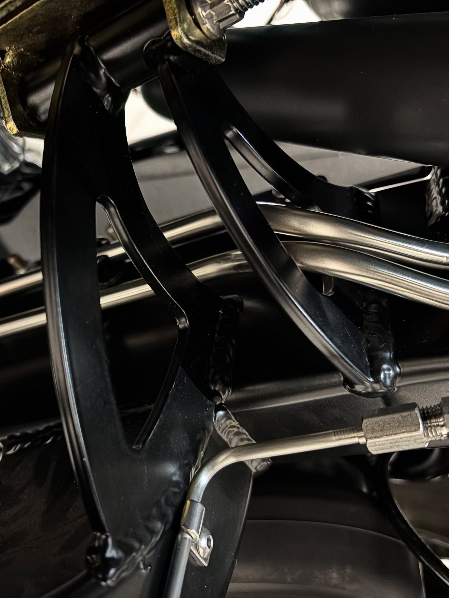 Close-up of glossy black metal brackets and chrome tubing in a mechanical frame