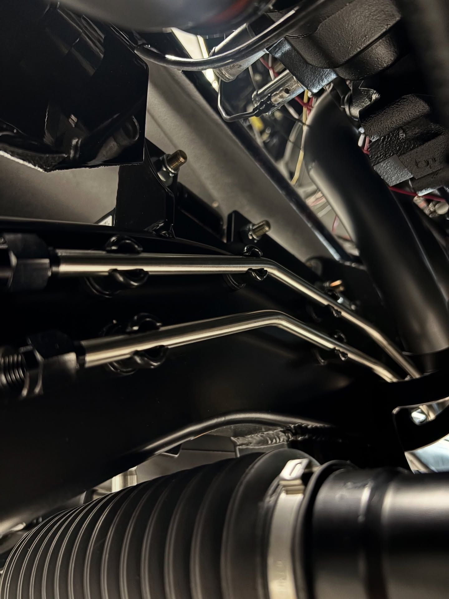 Close-up of motorcycle engine components and chrome linkage under the bodywork