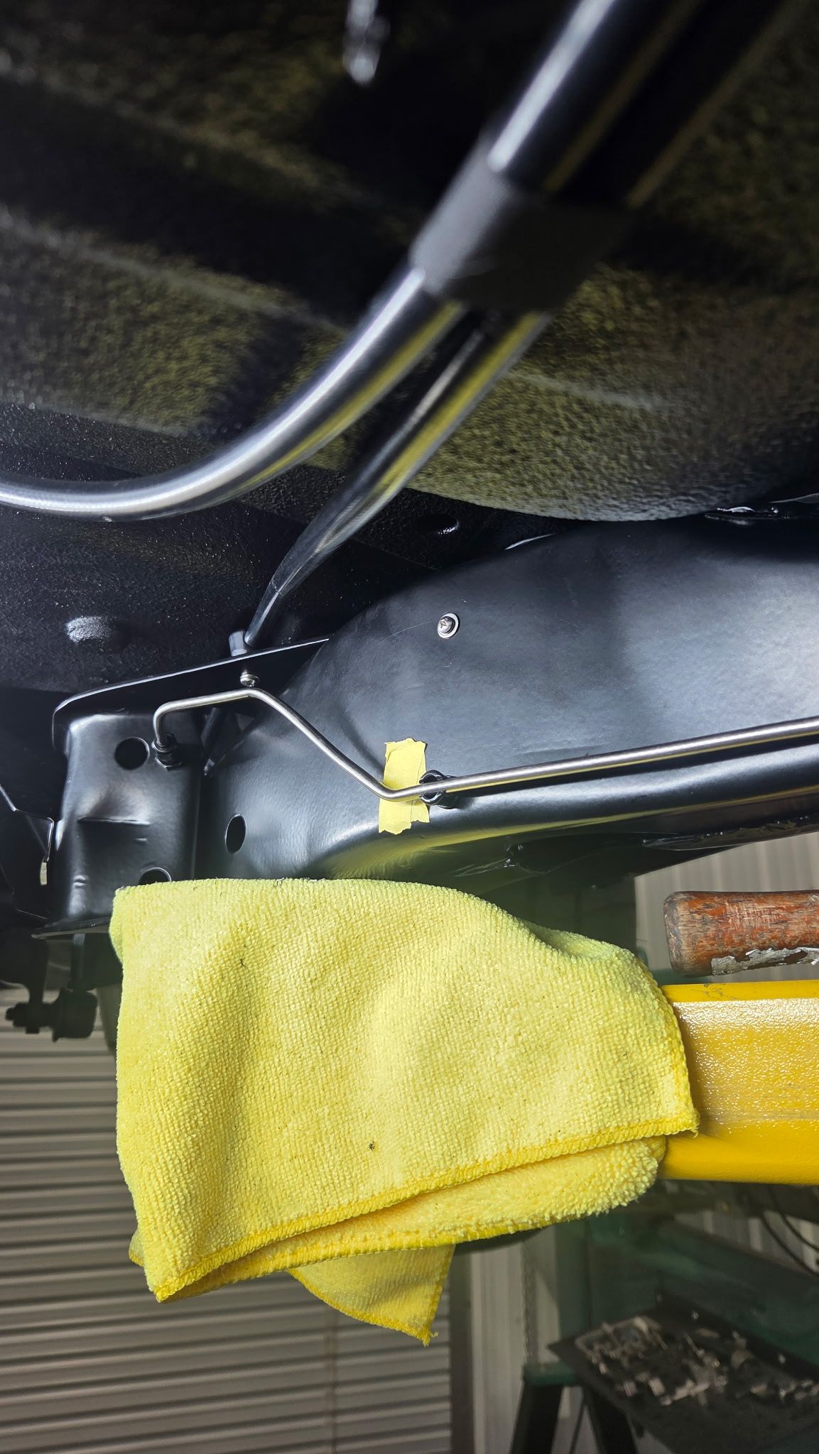 Yellow cloth draped over a black metal frame with tubes and bolts in an industrial-looking interior