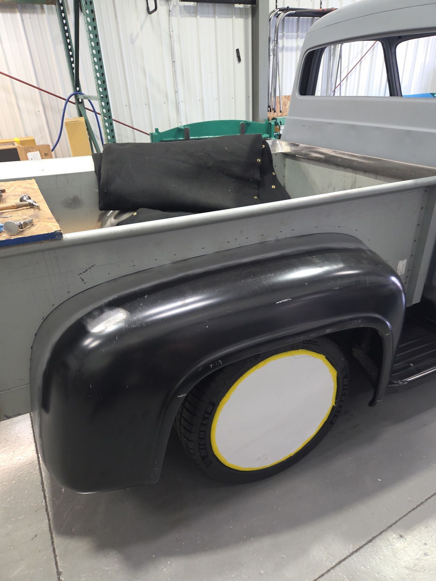 Black wheel arch panel with a white wheel inside a workshop setting