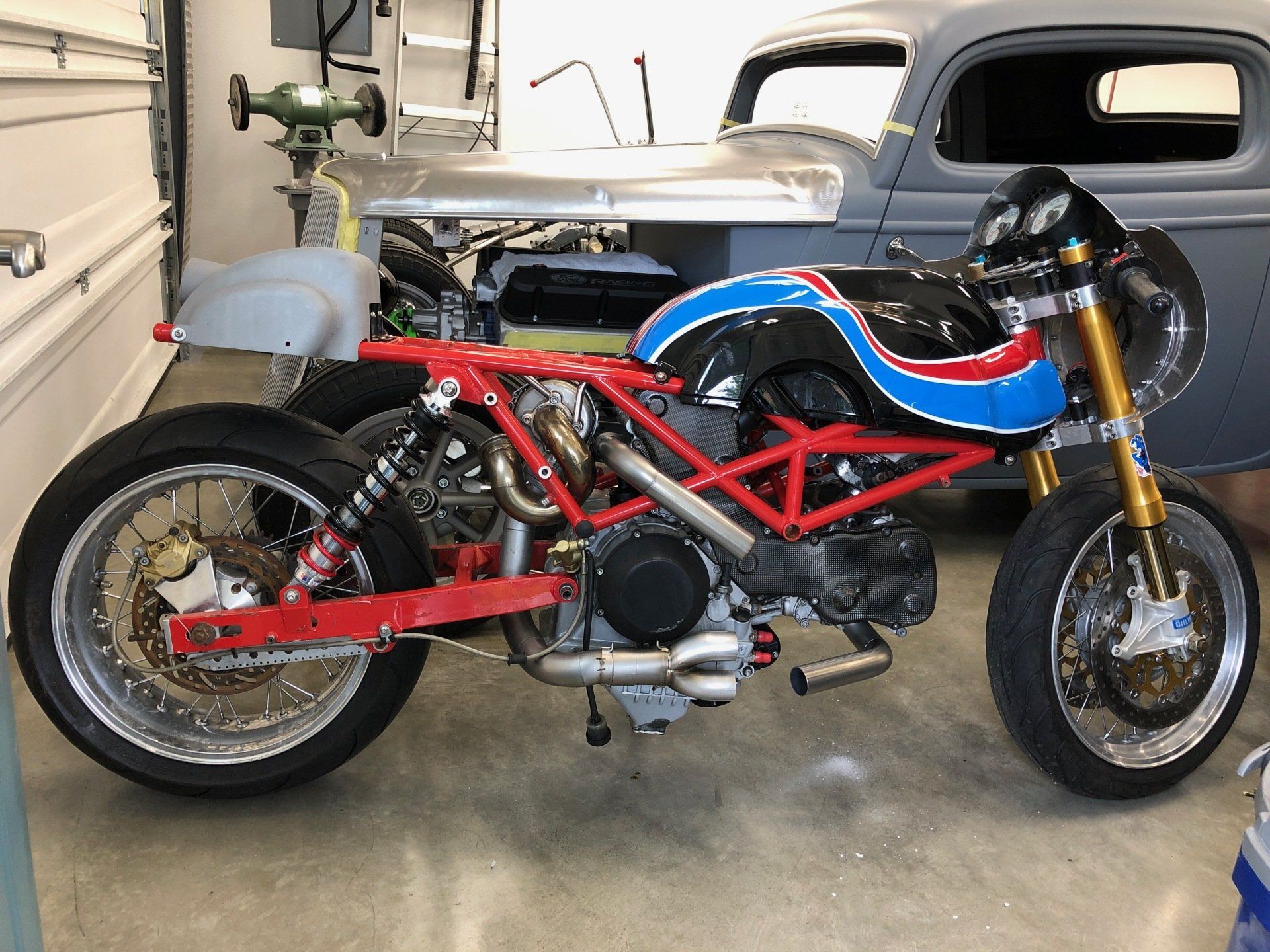 Red and blue sport motorcycle in a garage with a white pickup truck behind it