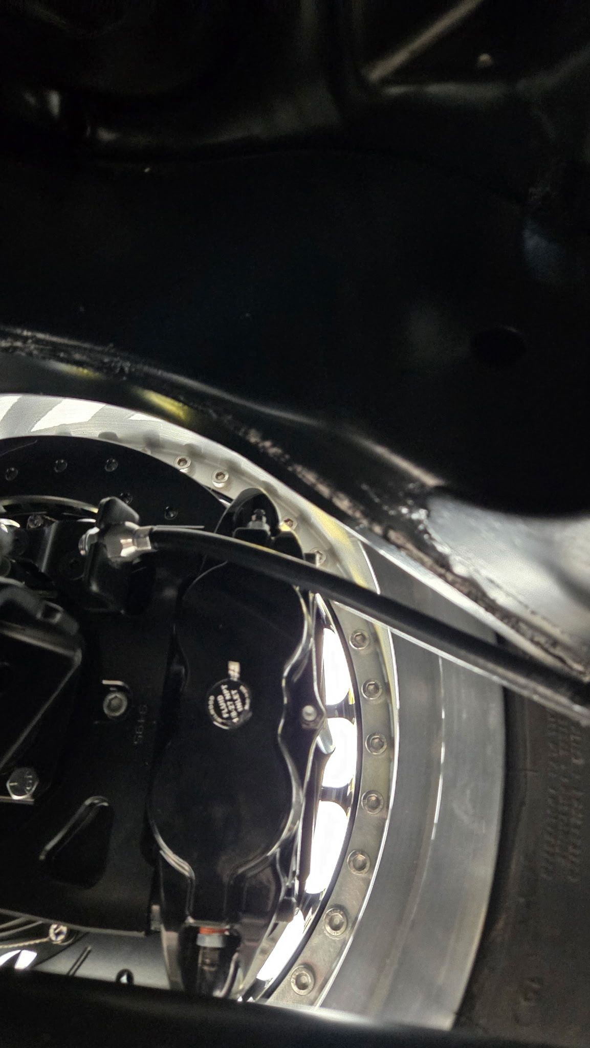 Close-up of a shiny mechanical wheel assembly with black and silver parts, lit by dim reflections
