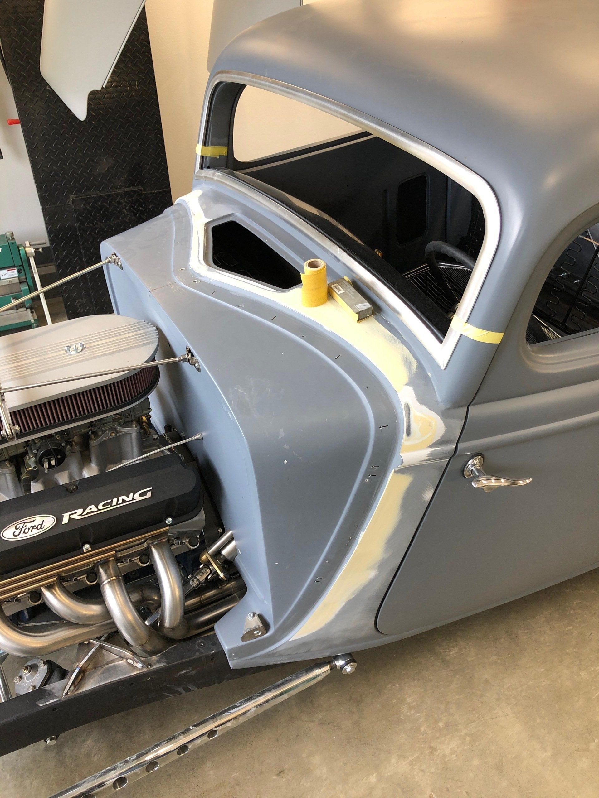 Blue custom hot rod with exposed engine and gray roof, shown in a workshop