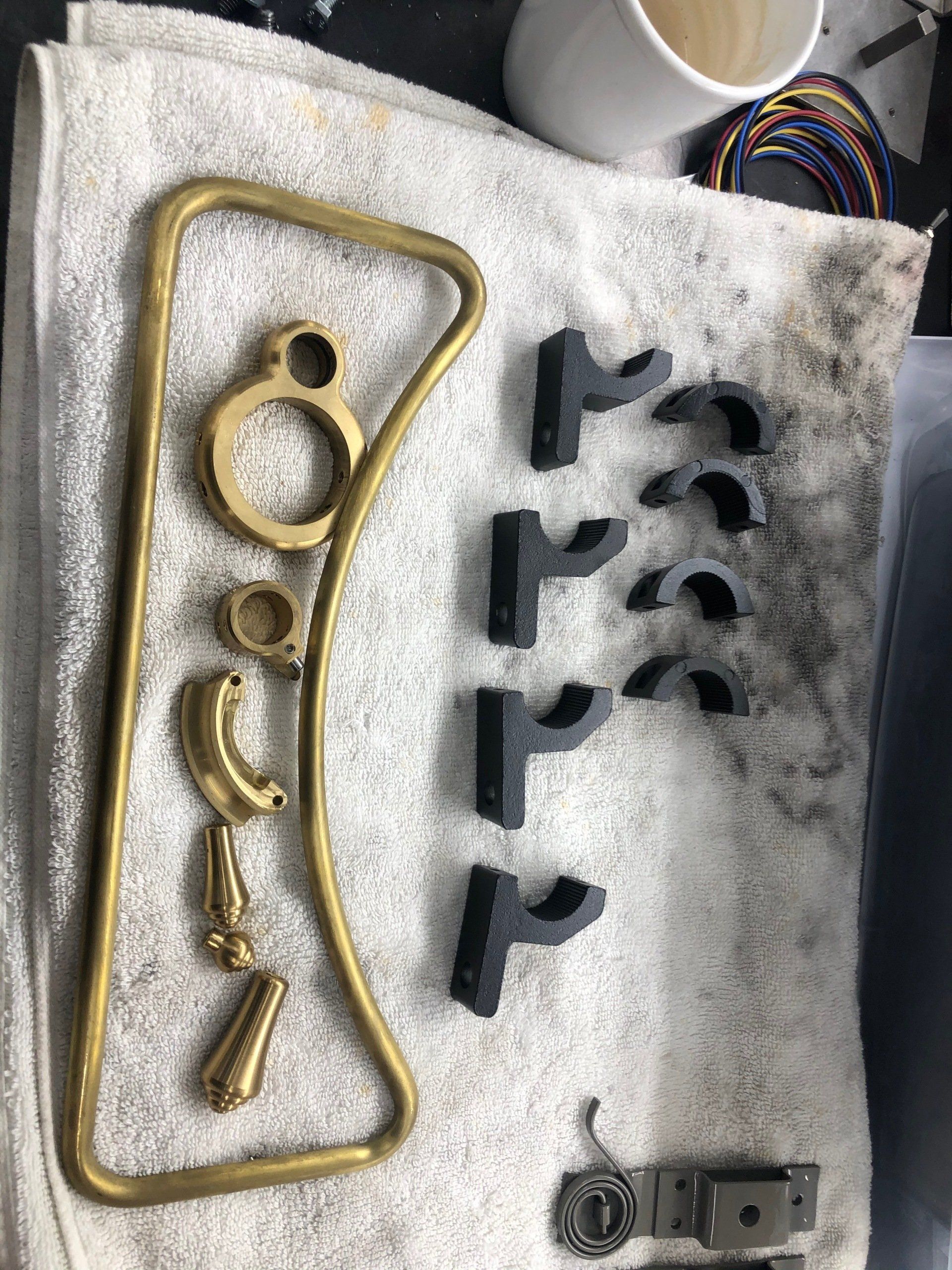 Six gold and black metal hardware pieces laid out on a white cloth.