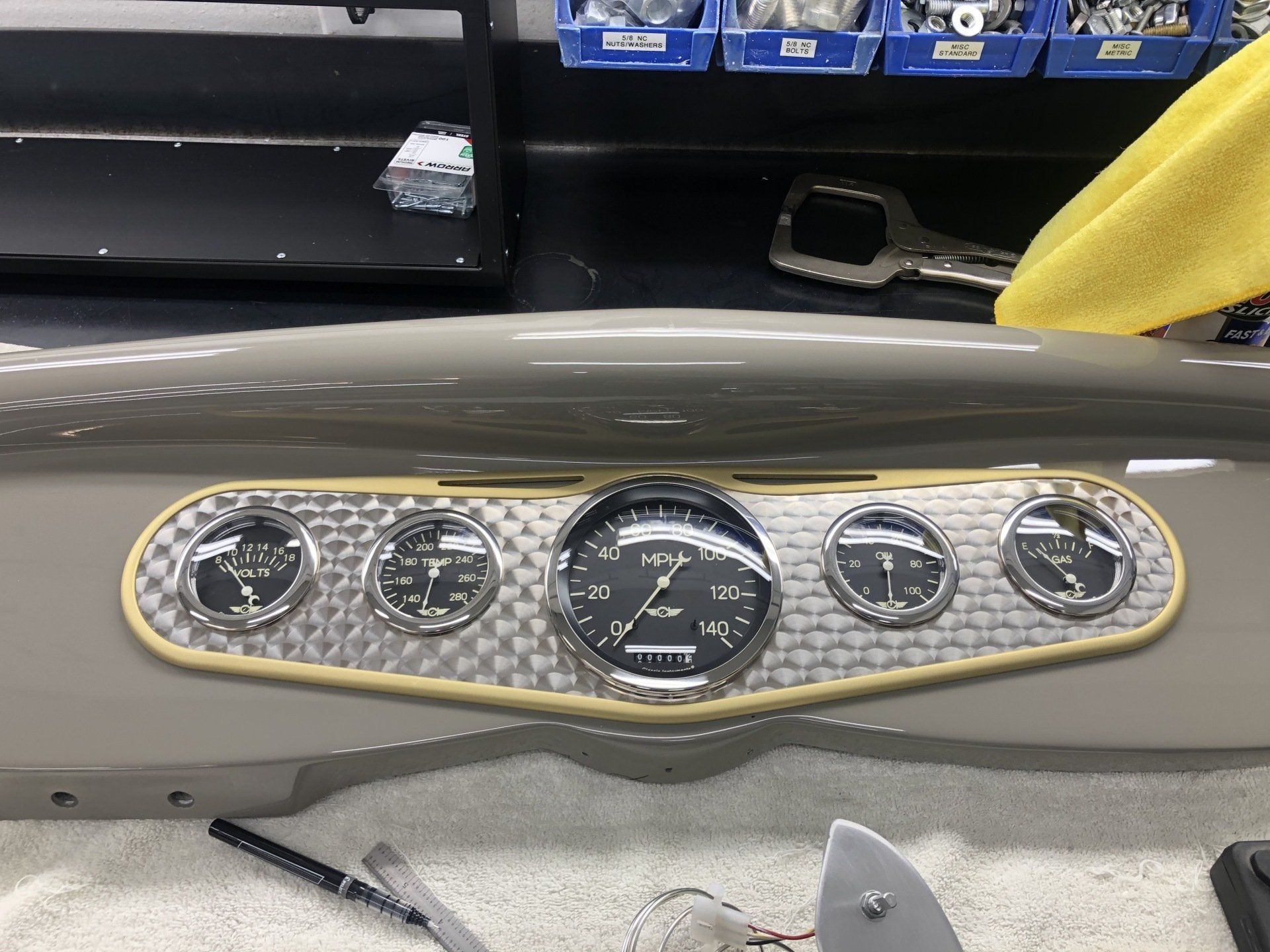 Classic dashboard with five gauges in a gray and gold car interior.
