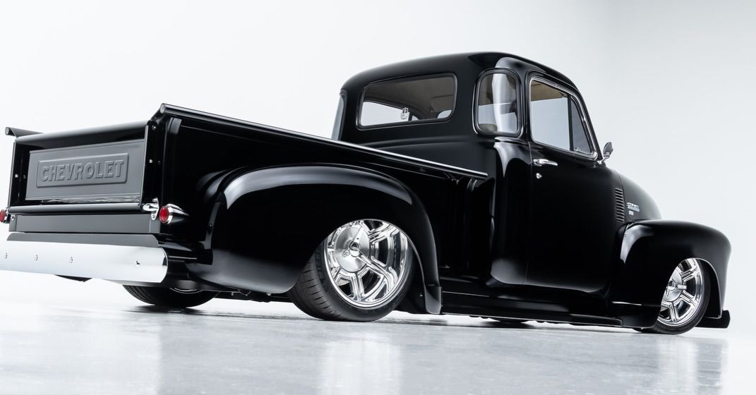 Black vintage pickup truck with chrome wheels on a white studio background
