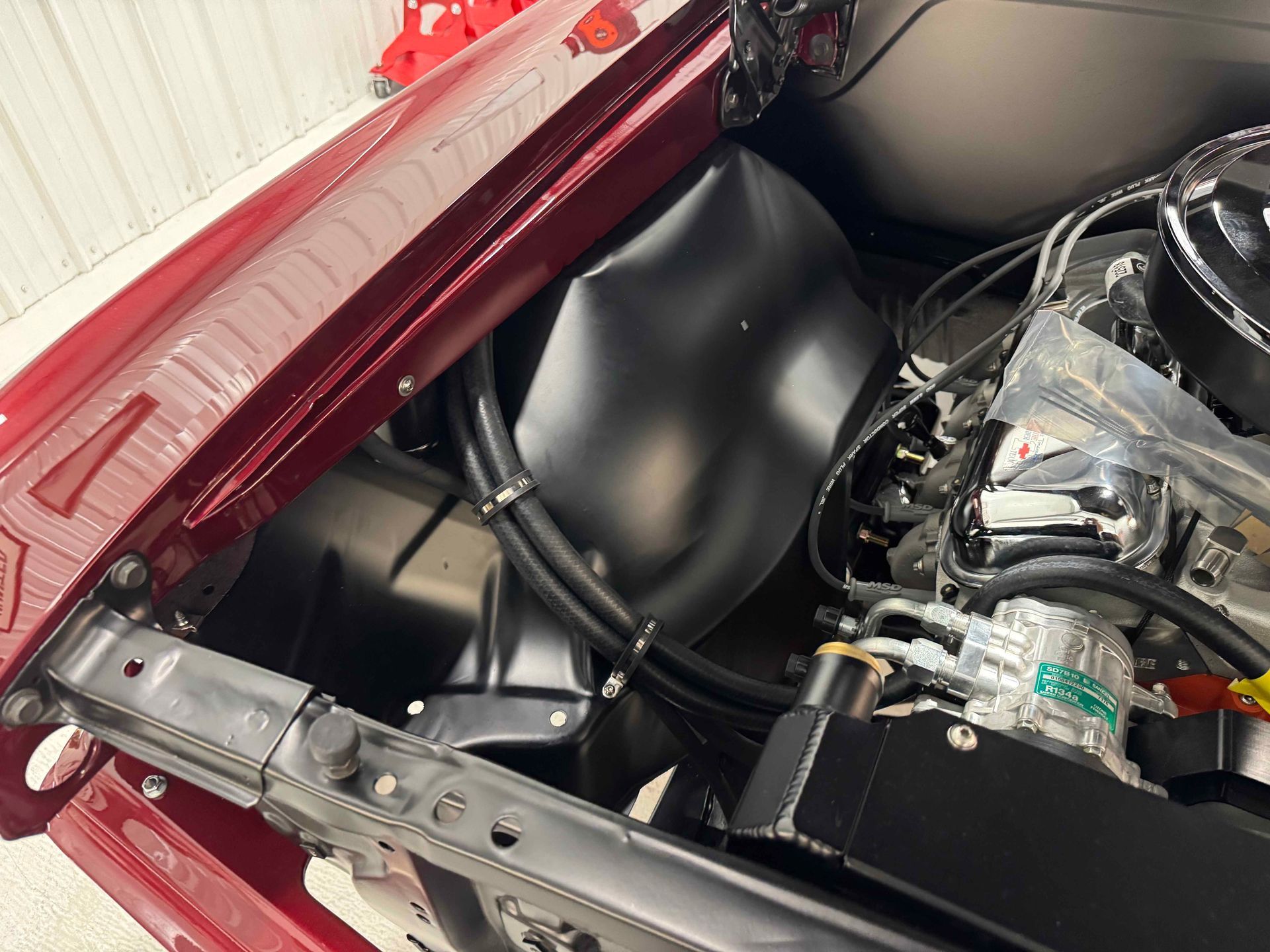 Close-up of a car trunk interior with red body panels, black liner, and engine parts visible