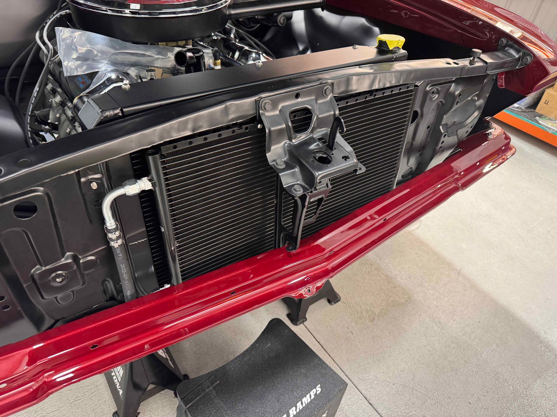 Close-up of a car’s open front grille and radiator behind a red bumper cover