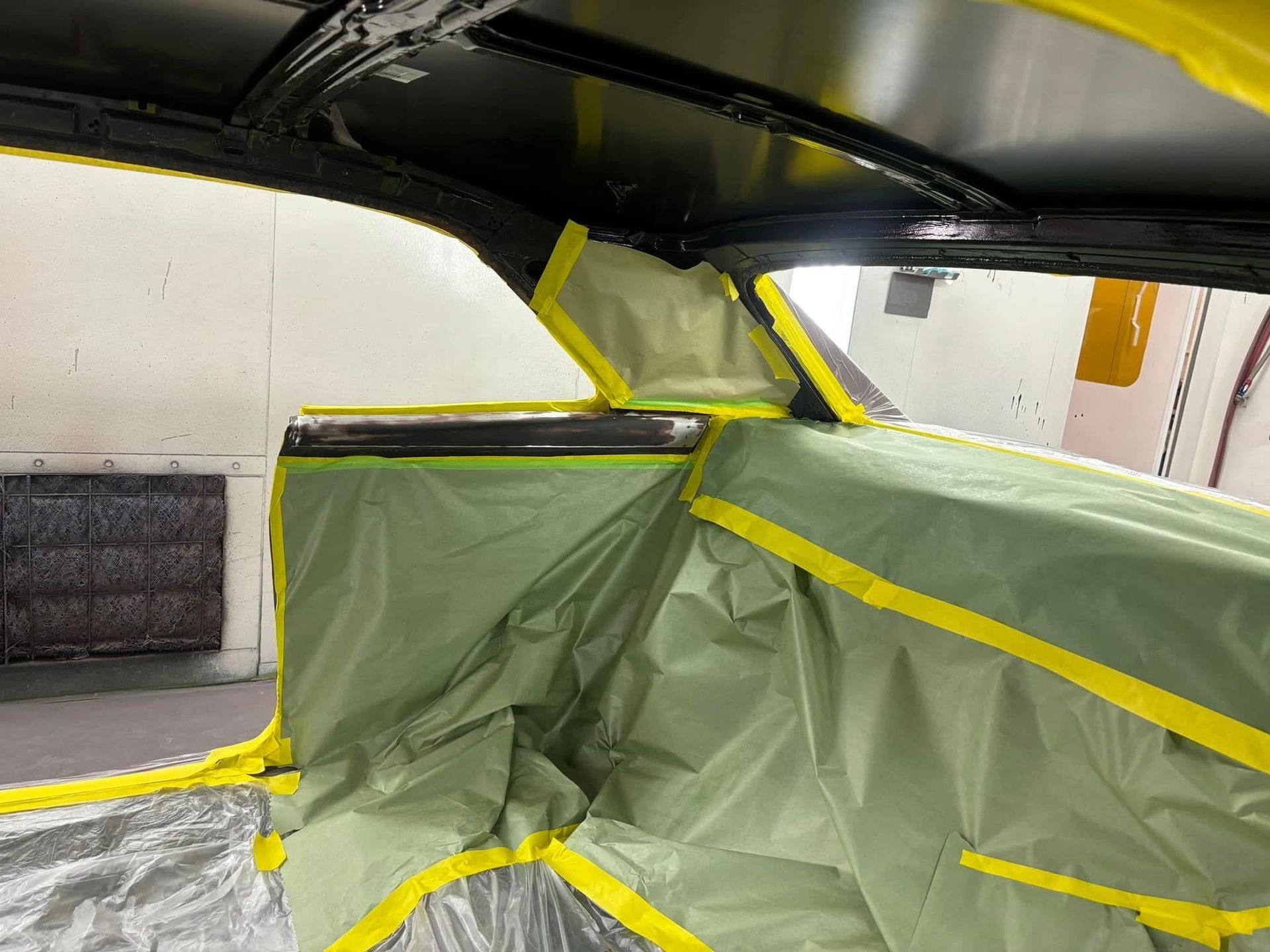 Green tarp-lined enclosed space under a black ceiling with yellow tape sealing the edges