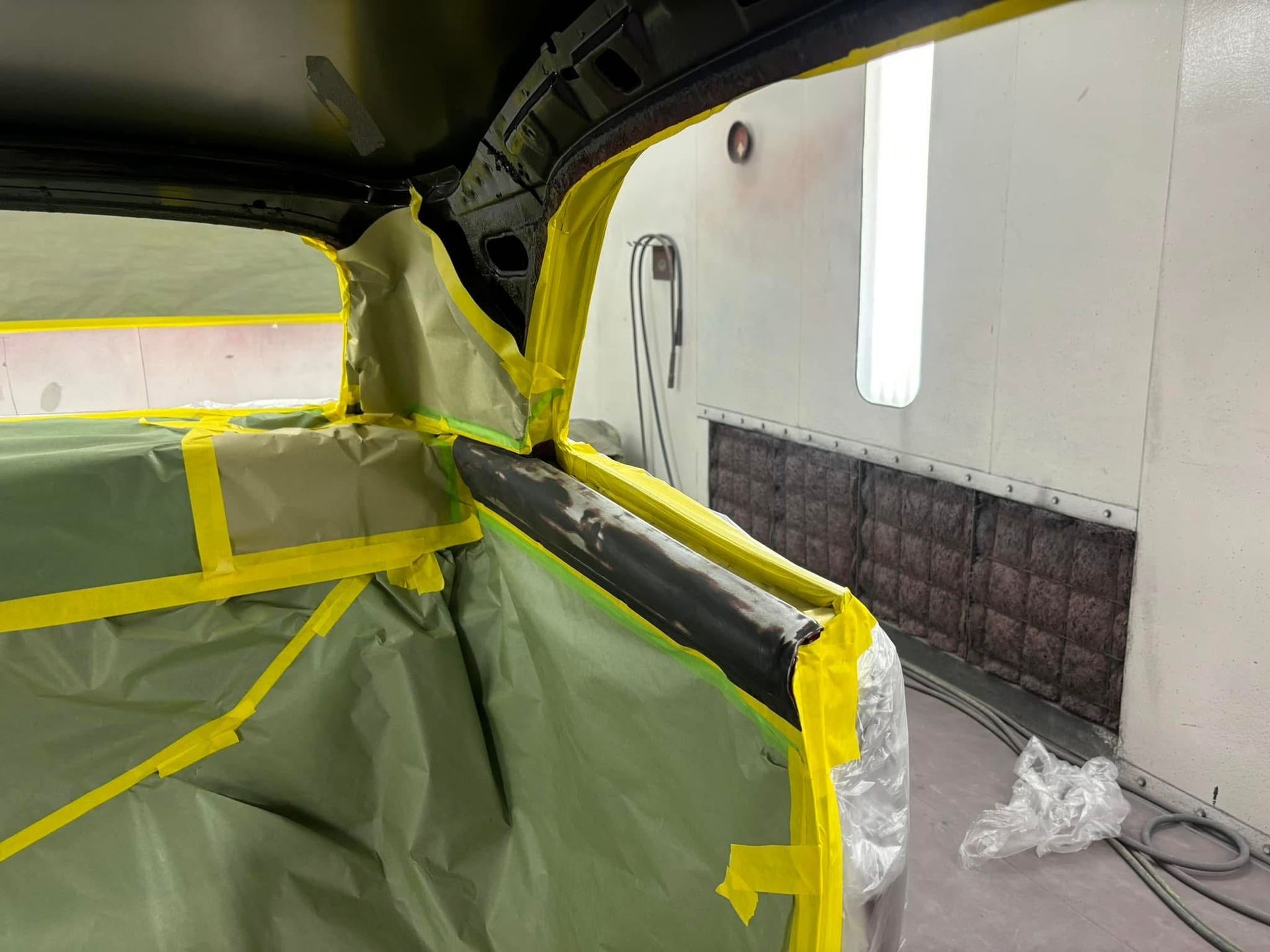 Masked car interior with yellow tape and plastic sheeting during paint or repair work